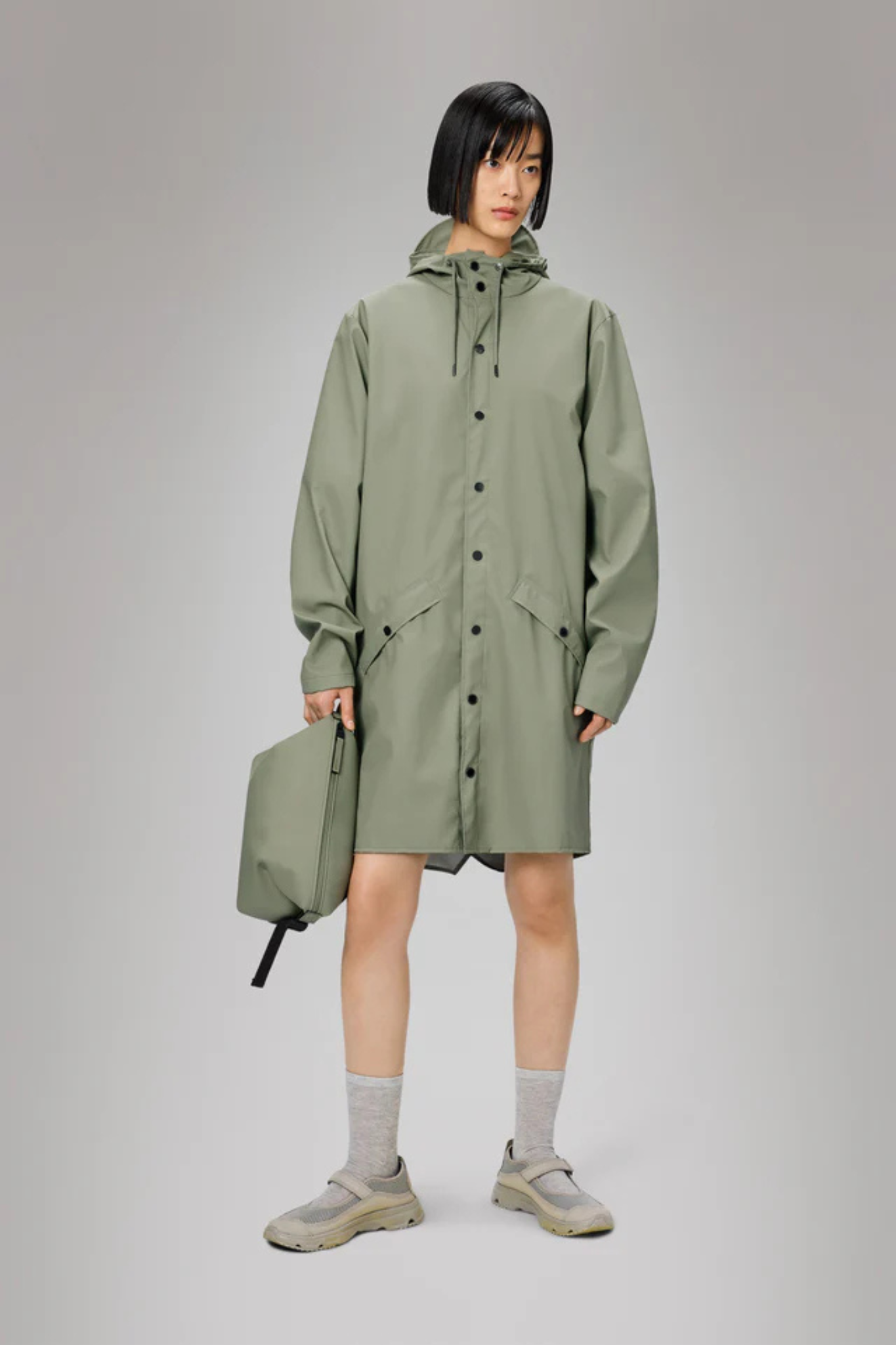 Model wearing the Rains long jacket W3 in green. Front view
