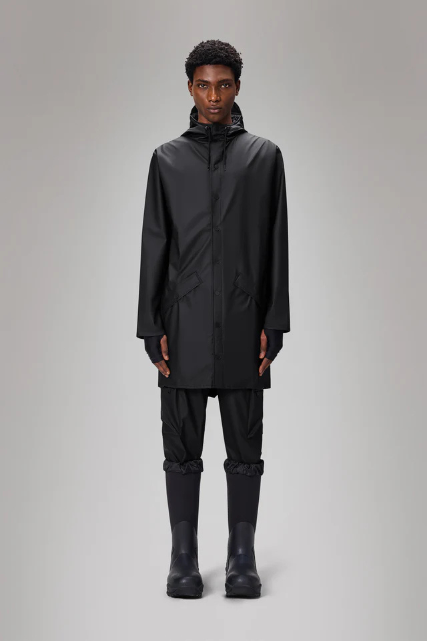 Model wearing the Rains long jacket W3 in black. Front view