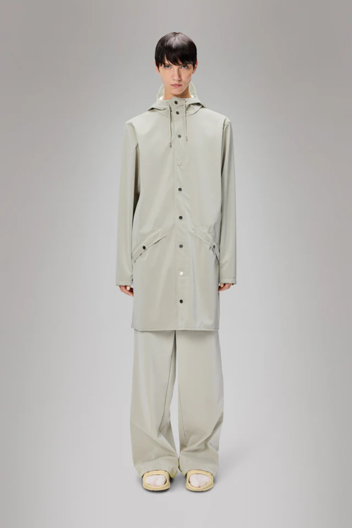 Model wearing the Rains long jacket W3 in white. Front view