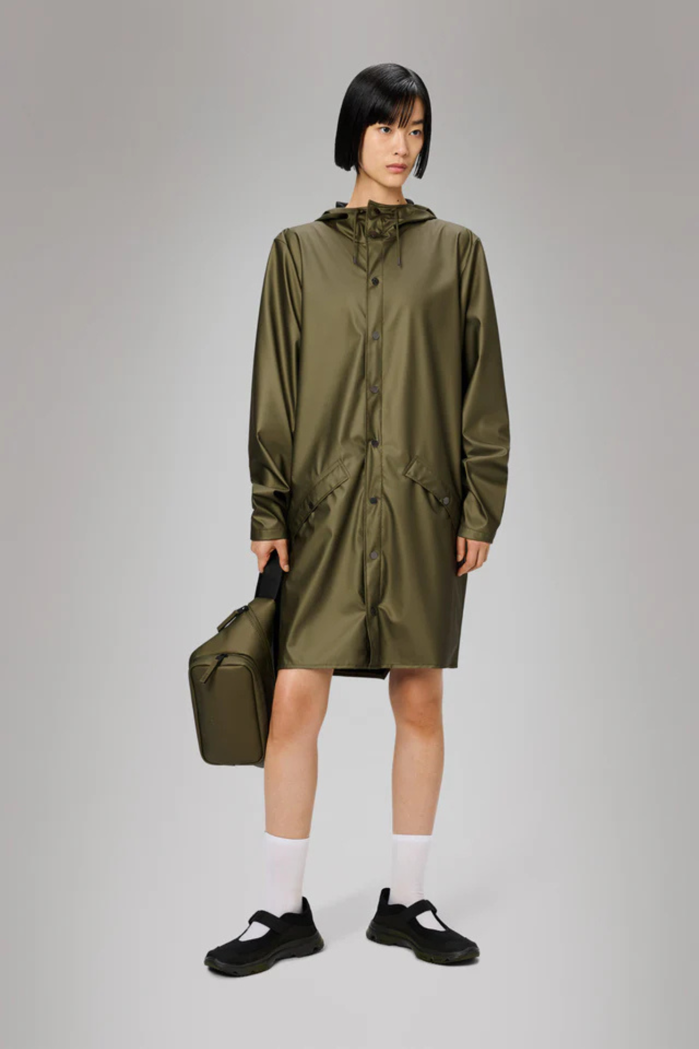 Model wearing the Rains long jacket W3 in khaki. Front view