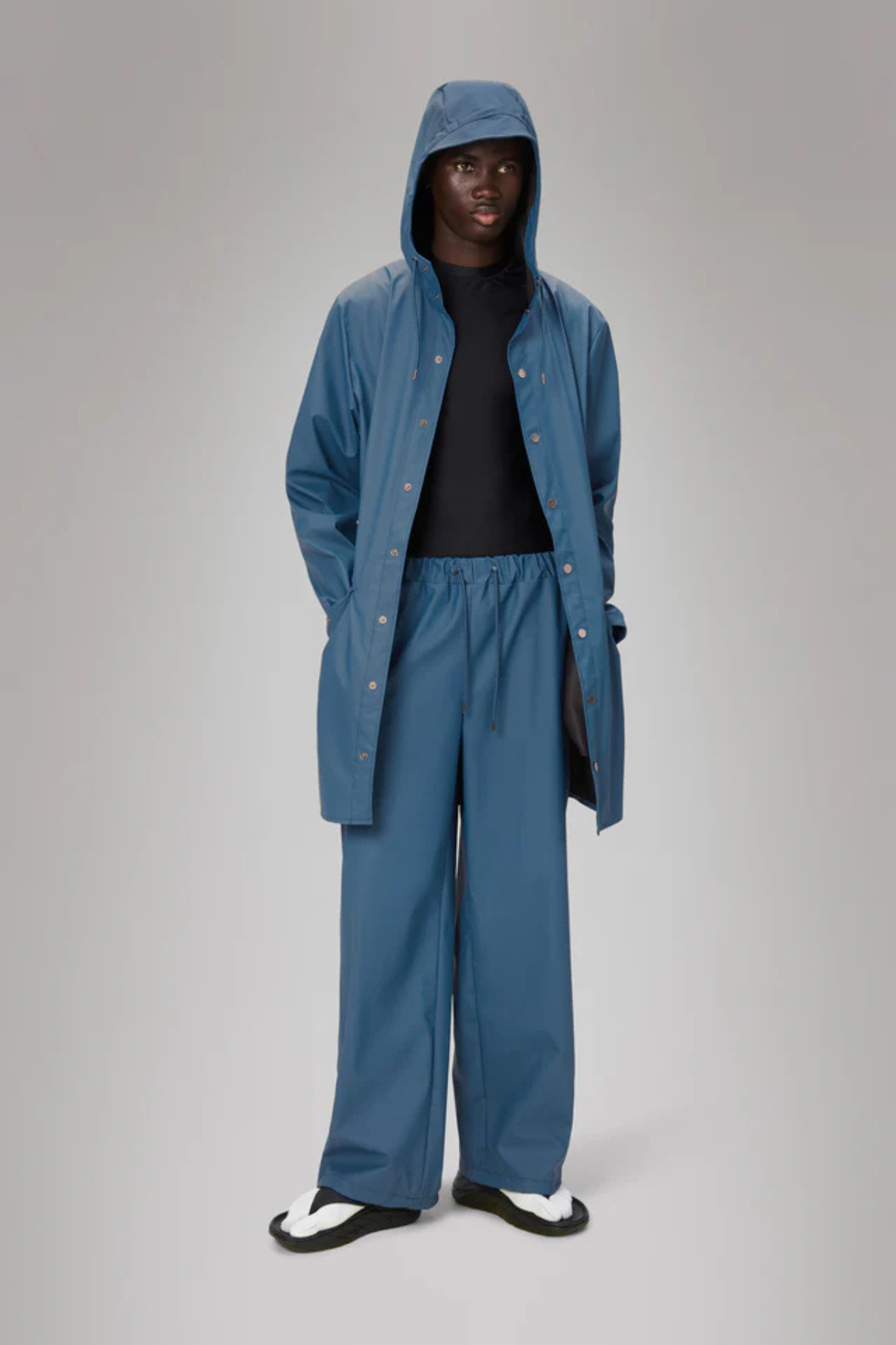 Model wearing the Rains long jacket W3 in blue. Front view