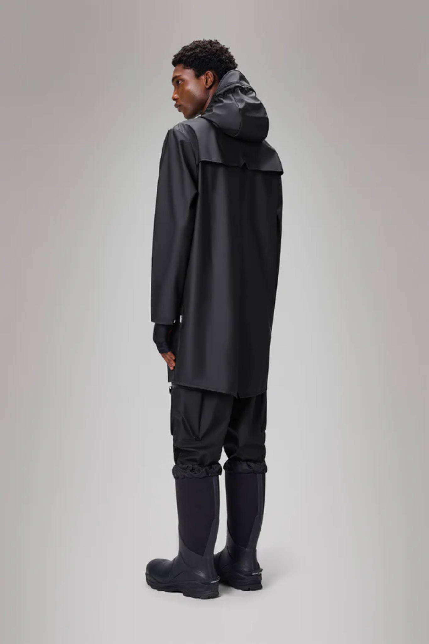 Model wearing the Rains long jacket W3 in black. Back view