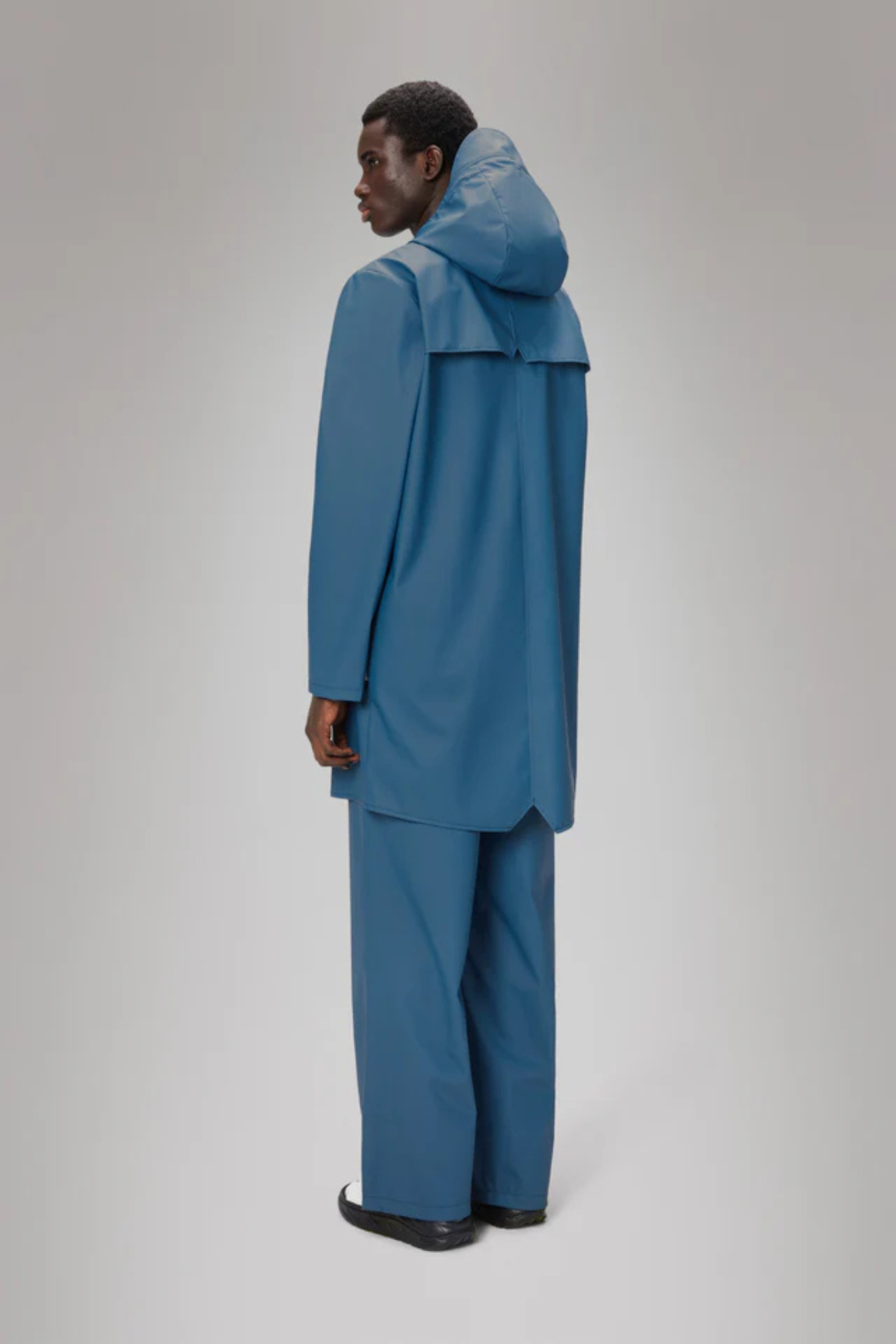 Model wearing the Rains long jacket W3 in blue. Back view