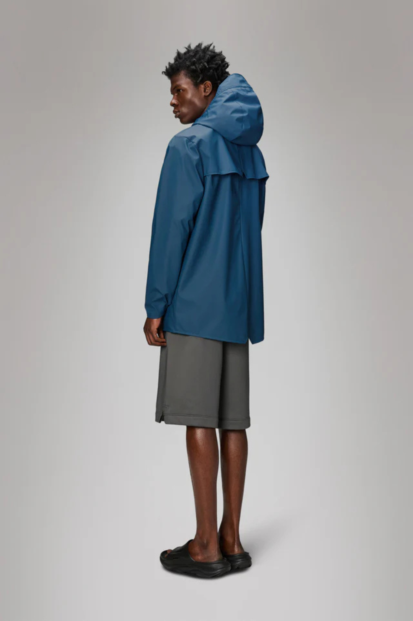 Model wearing the Rains jacket W3 in blue. Back view