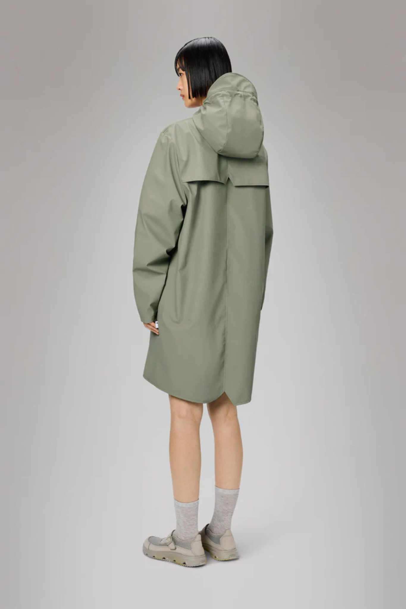 Model wearing the Rains long jacket W3 in green. Back view