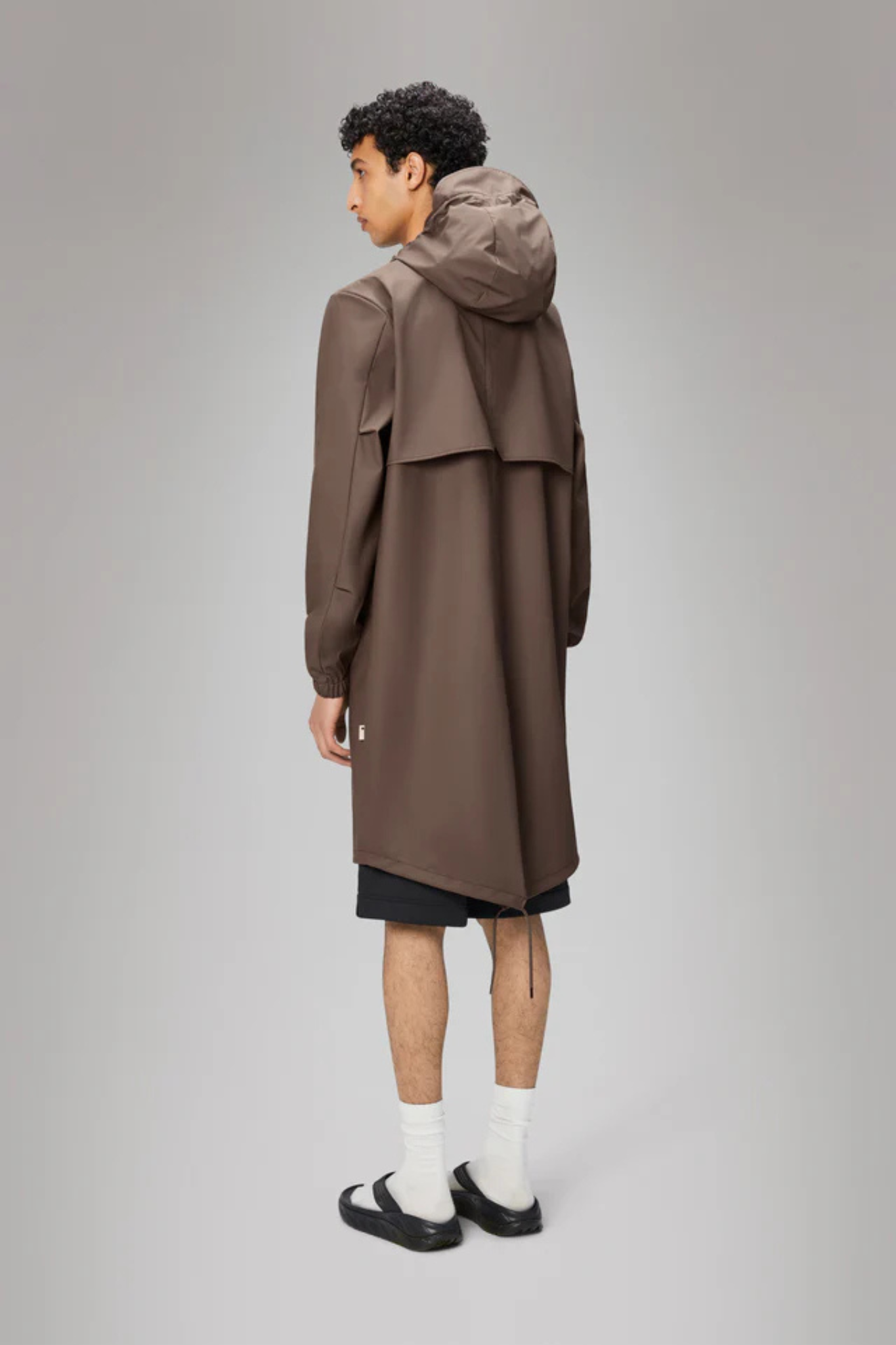 Model wearing the Rains fishtail parka W3 in shade. Back view