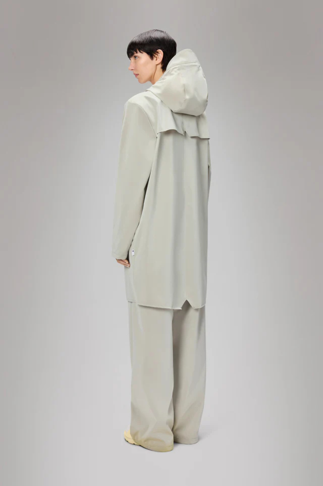Model wearing the Rains long jacket W3 in white. Back view
