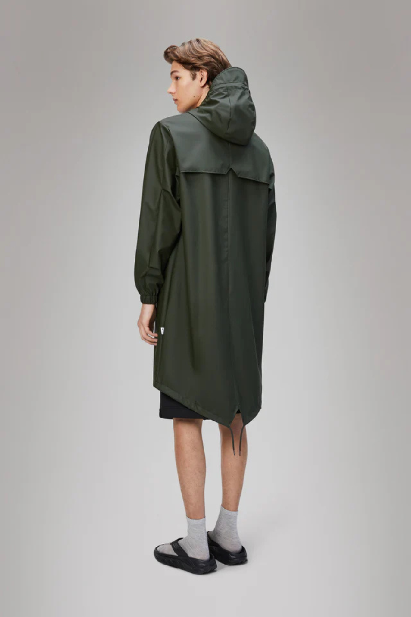 Model wearing the Rains fishtail parka W3 in green. Back view