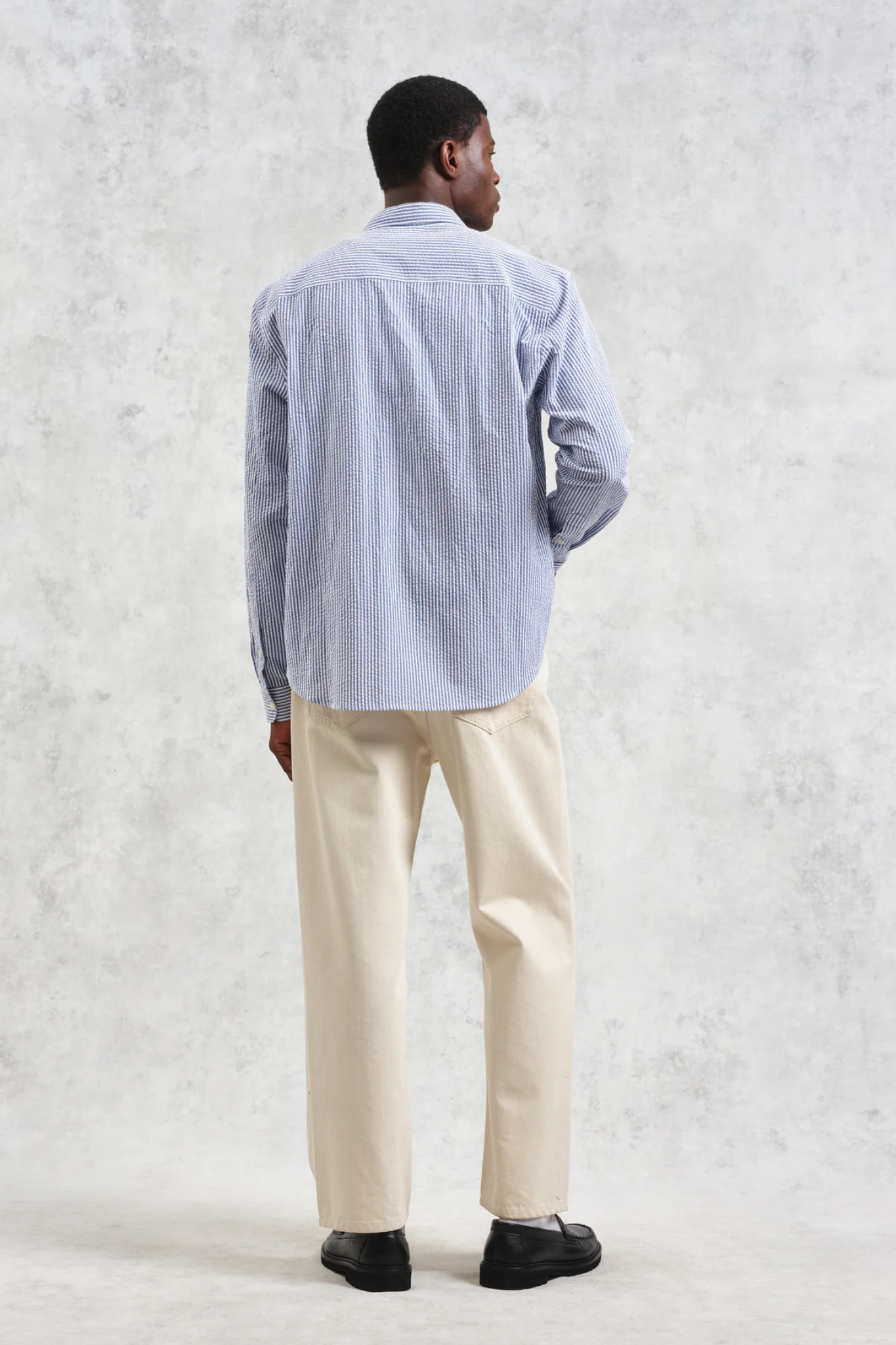 Model wearing the Wax London rove seersucker stripe shirt in blue. Back view