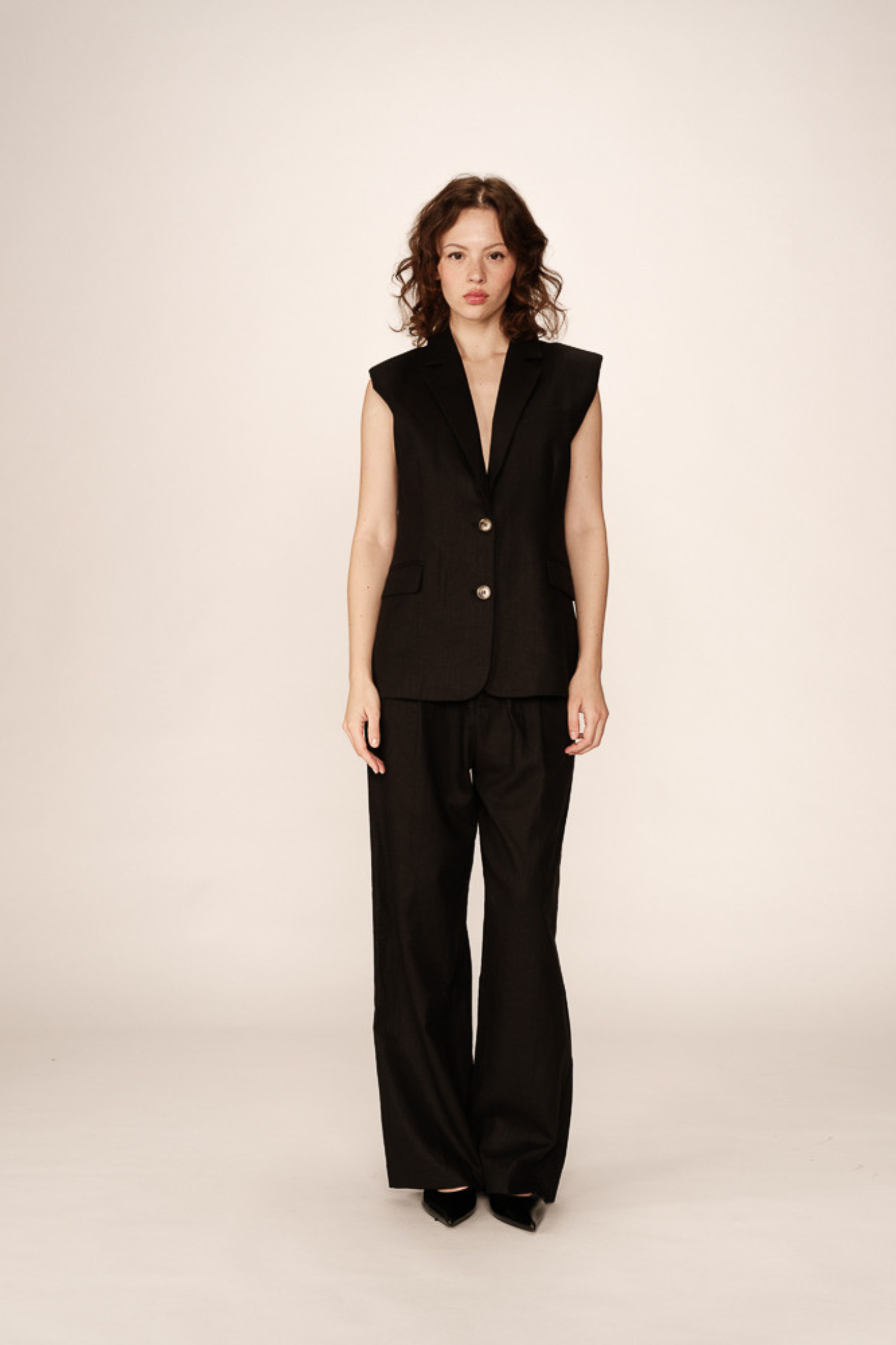 Model wearing the Grace & Mila pietro sleeveless blazer in black. Front view