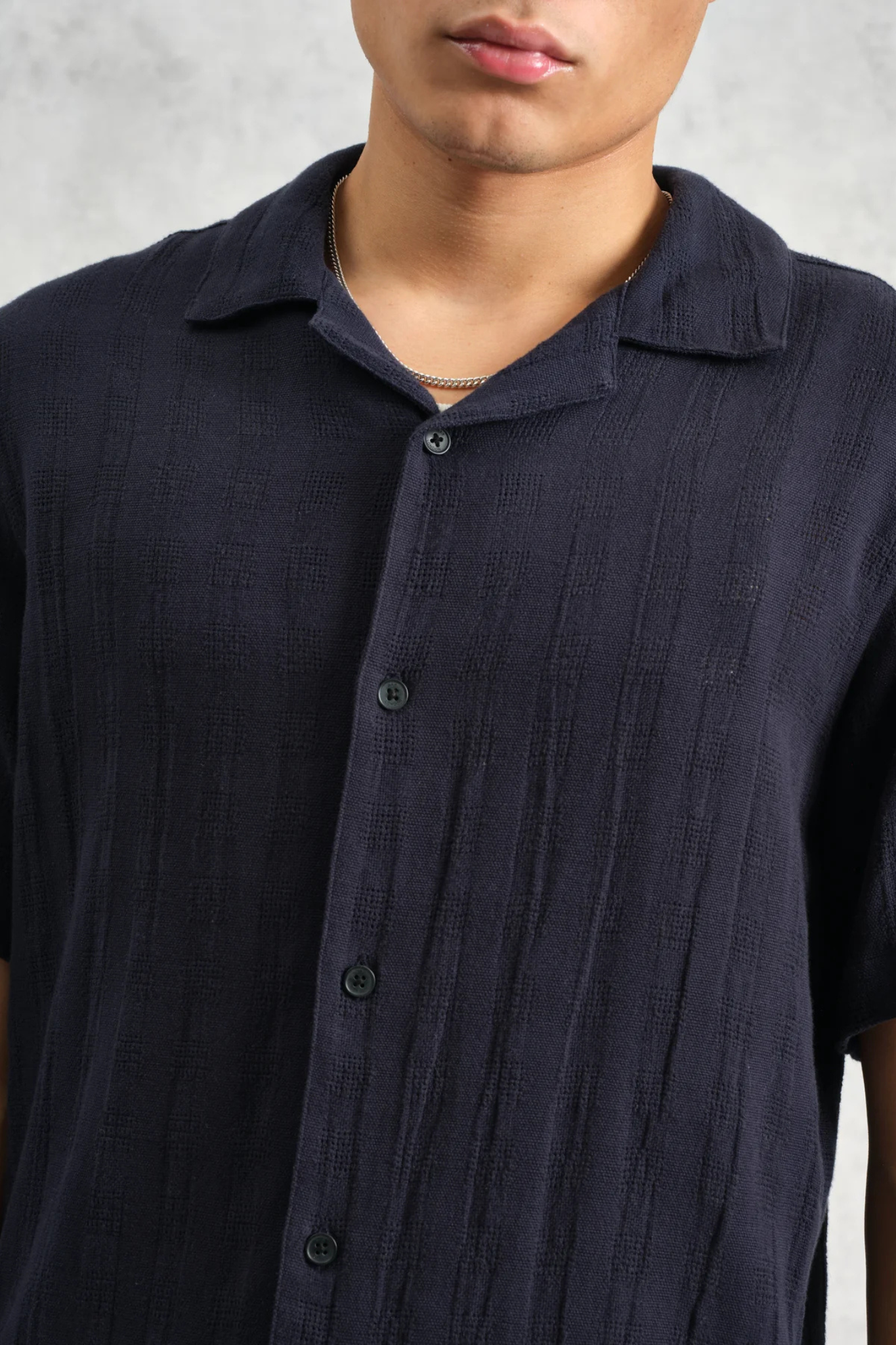 Model wearing the Wax London didcot box open weave grid shirt in navy. Close front view