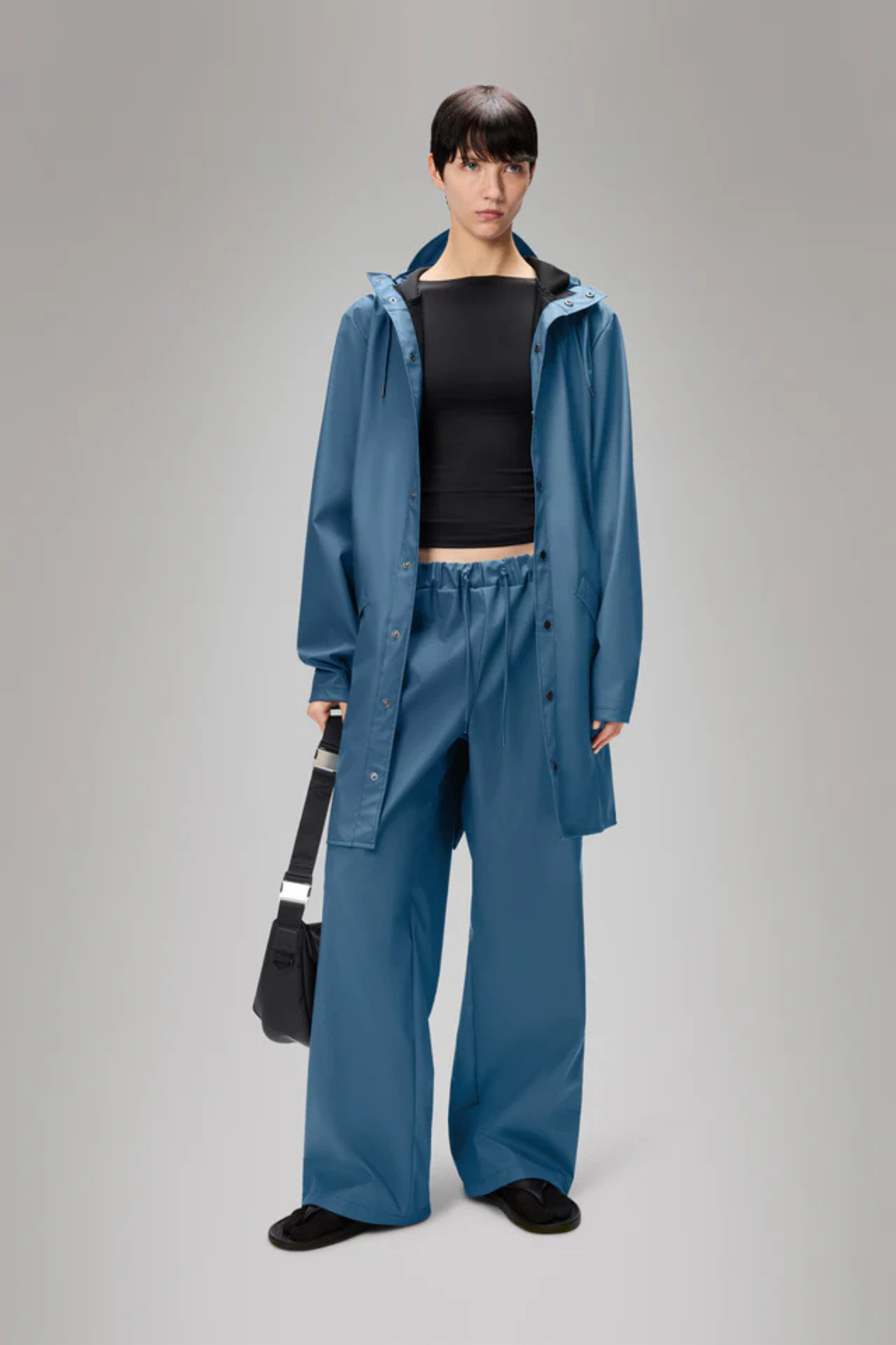 Model wearing the Rains long jacket W3 in blue. Front view
