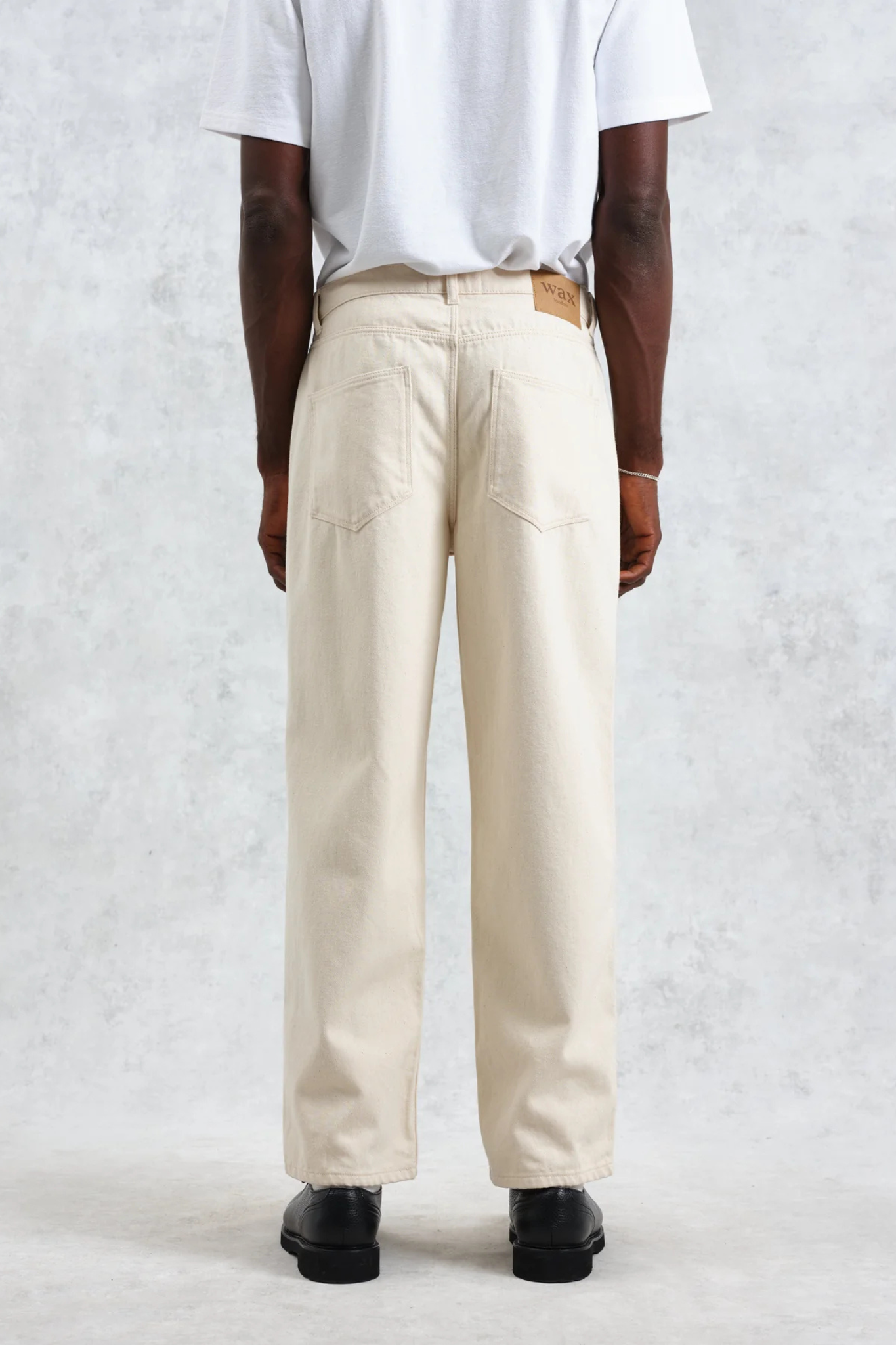 Model wearing the Wax London felix loose fit denim jeans in ecru. Back view