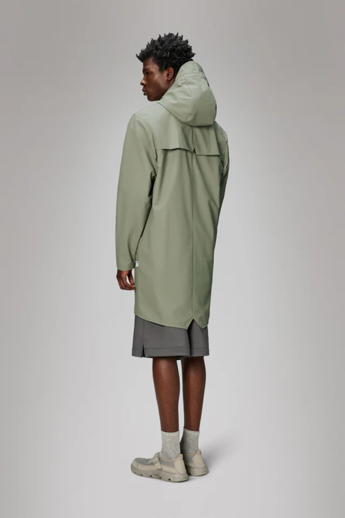 Model wearing the Rains long jacket W3 in green. Back view