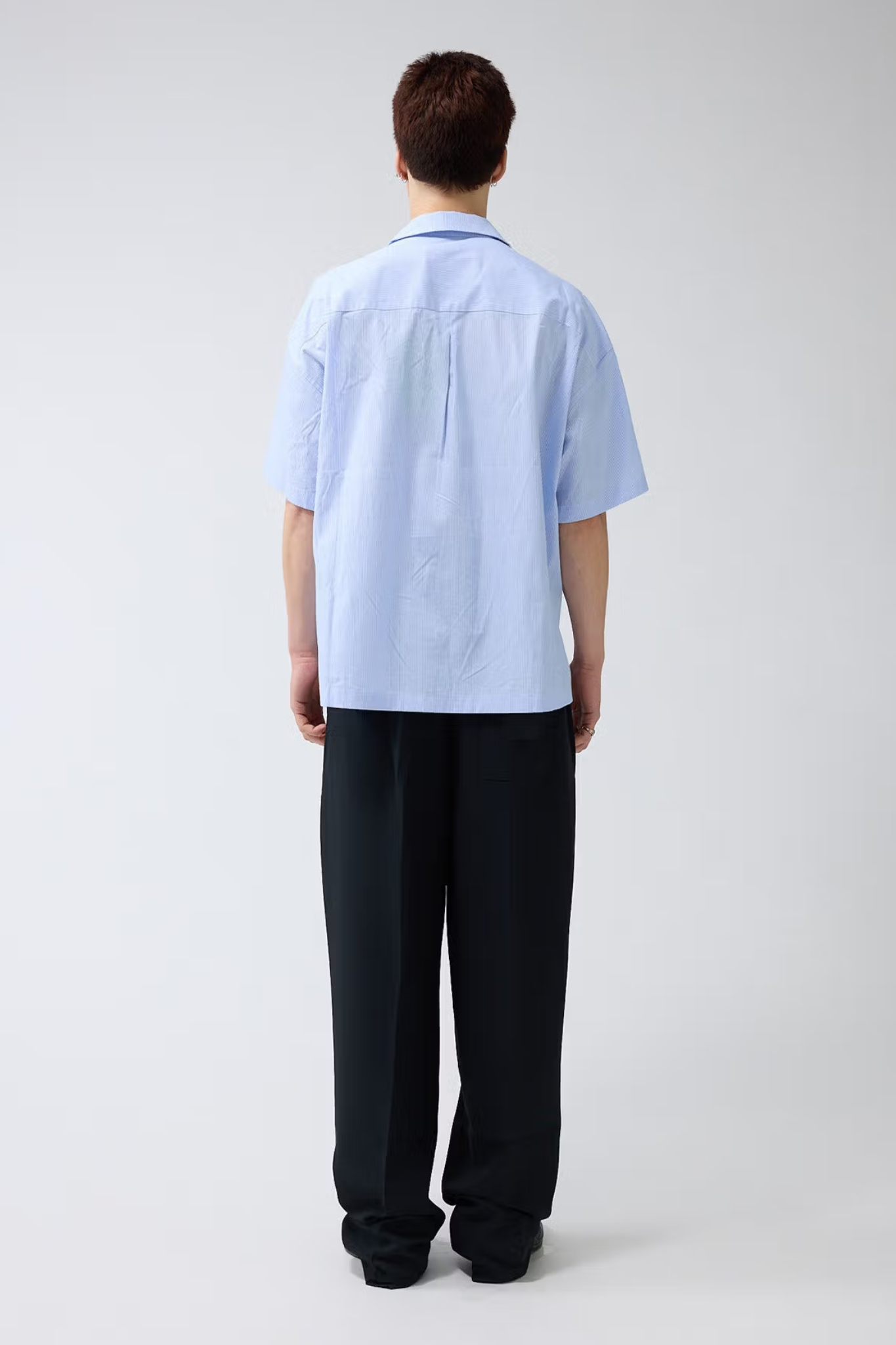 Model wearing the New Amsterdam wijk shirt in white/blue stripes. Back view