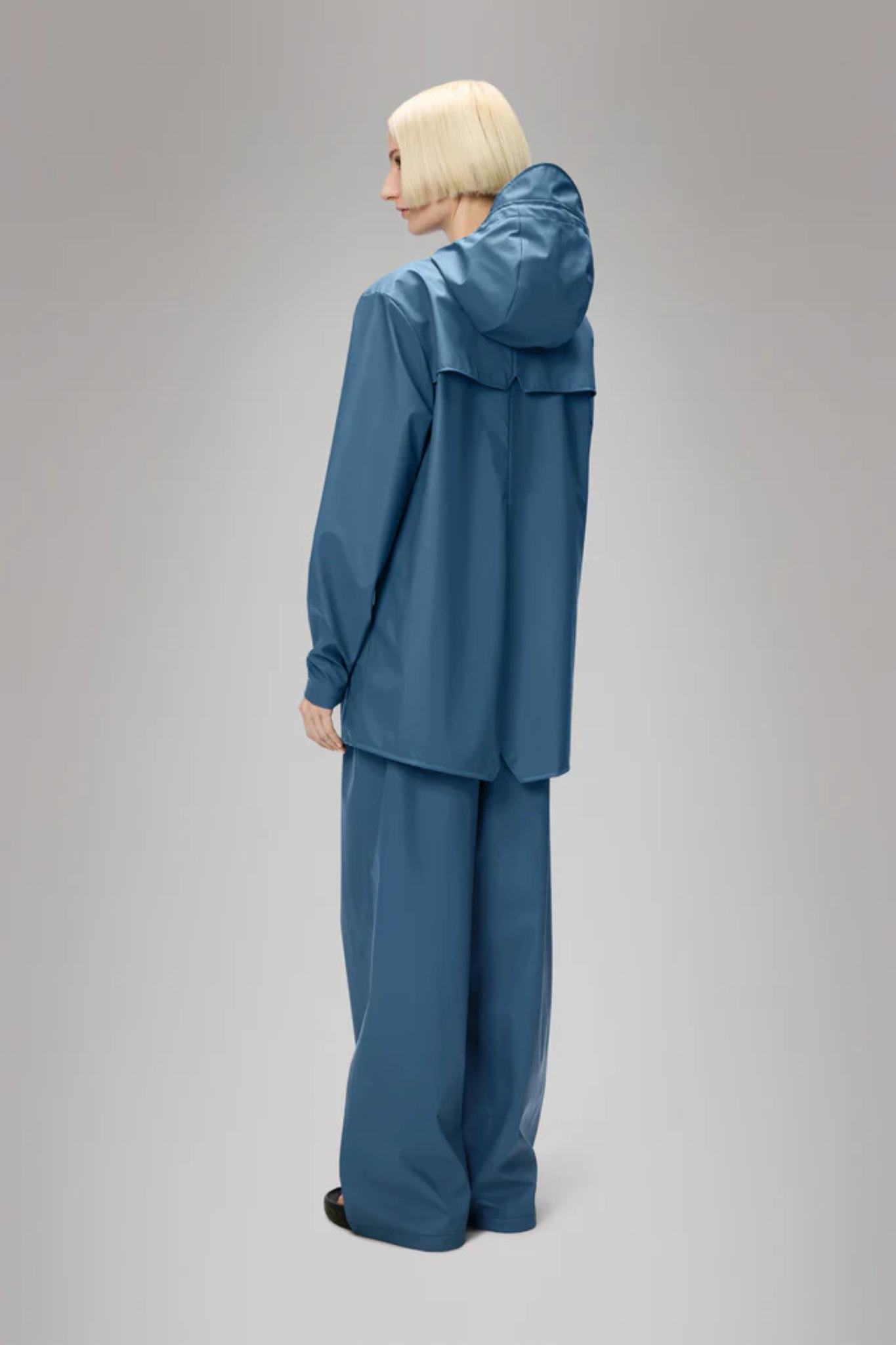 Model wearing the Rains jacket W3 in blue. Back view