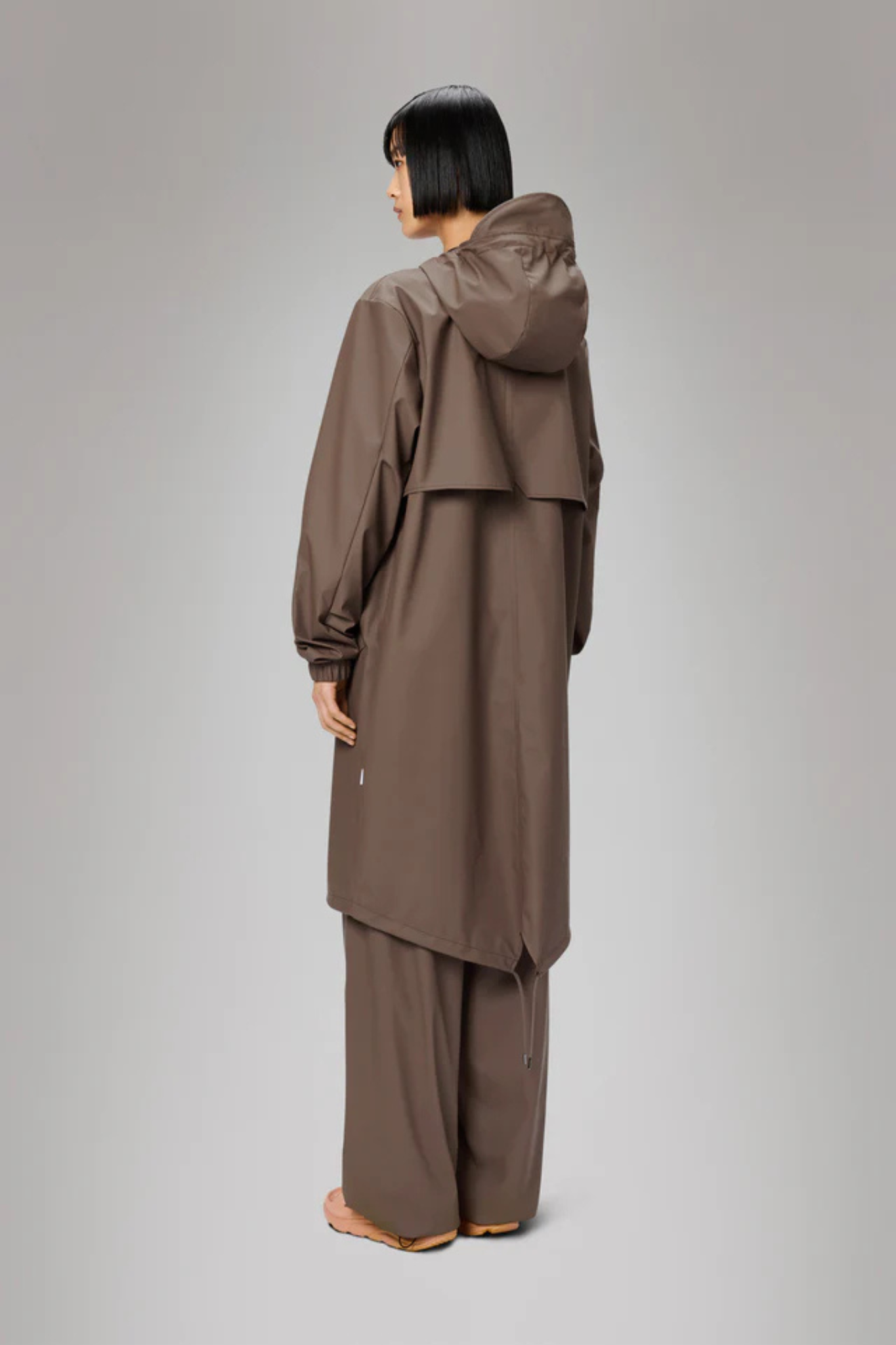 Model wearing the Rains fishtail parka W3 in shade. Back view