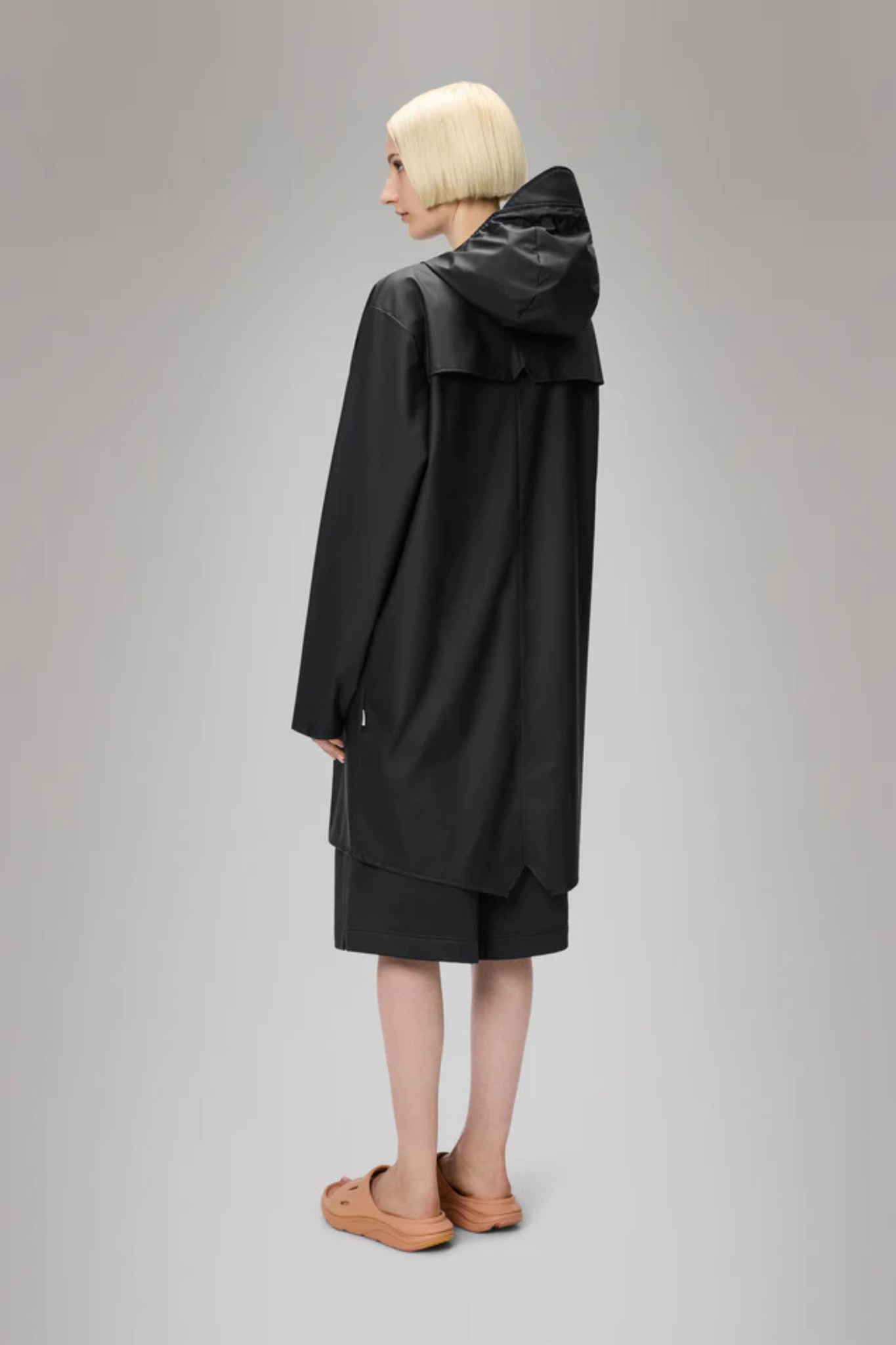 Model wearing the Rains long jacket W3 in black. Back view