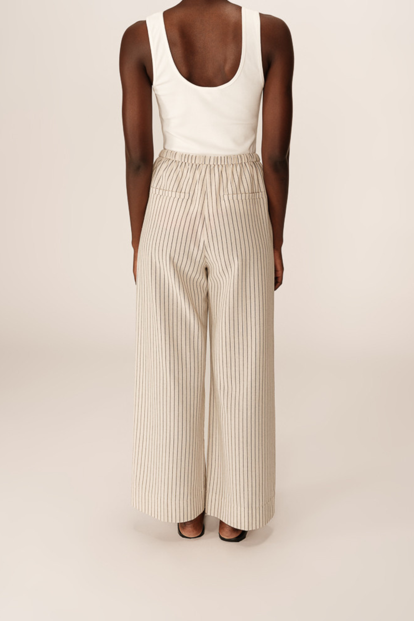 Model wearing the Grace & Mila perry pants in beige and black striped. Back view