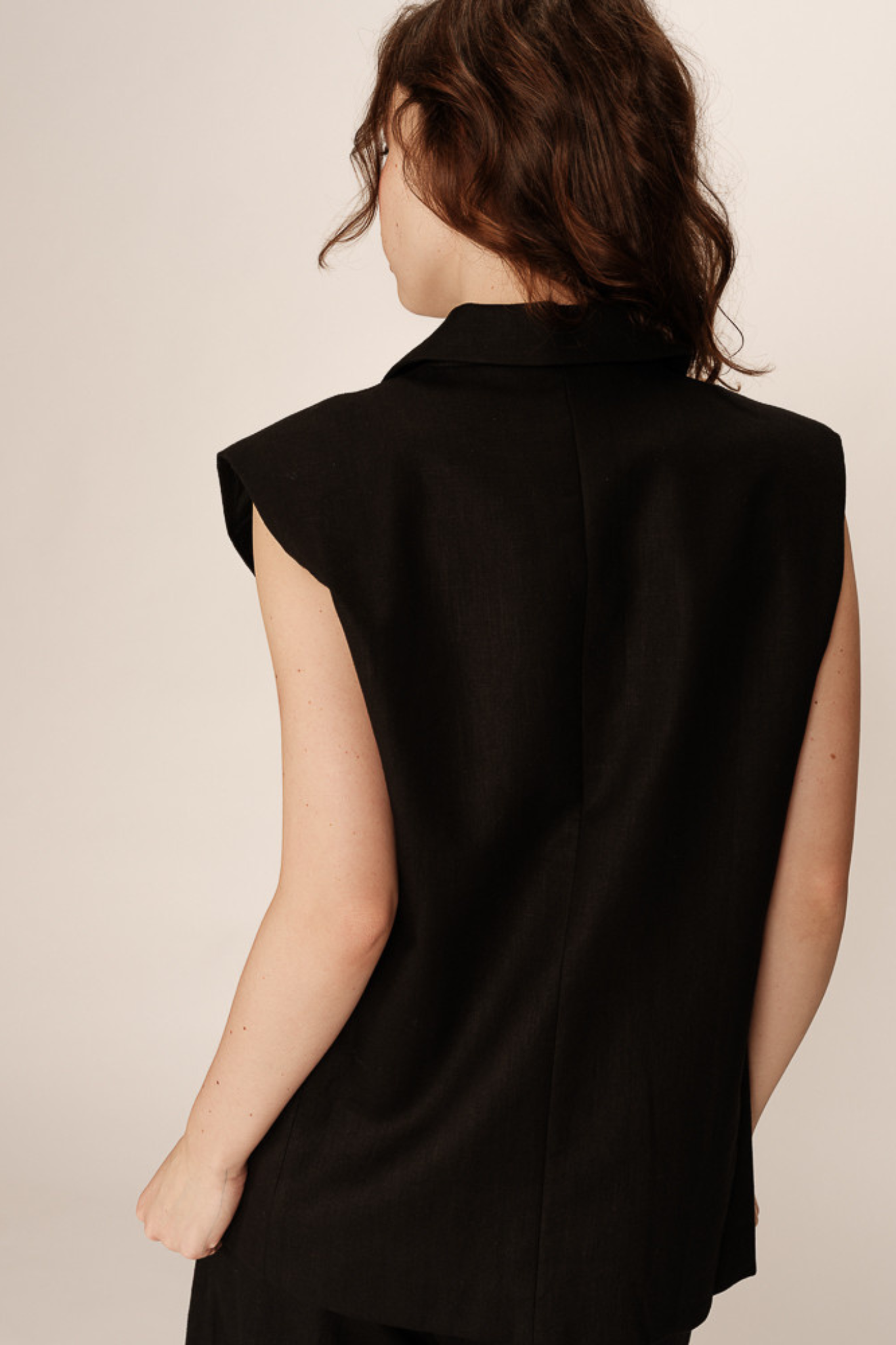Model wearing the Grace & Mila pietro sleeveless blazer in black. Back view