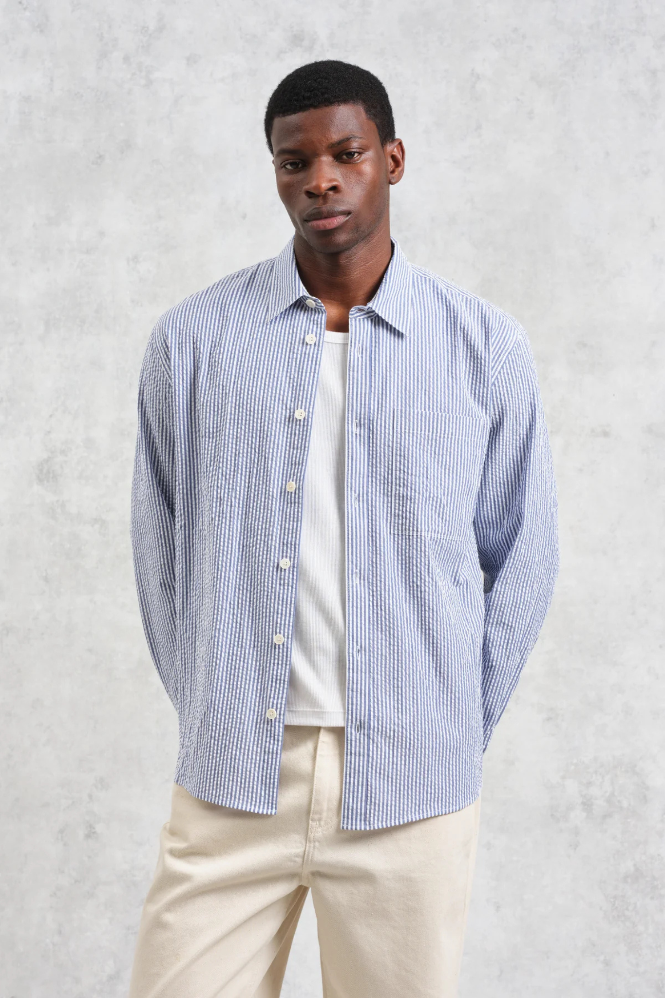 Model wearing the Wax London rove seersucker stripe shirt in blue. Front view