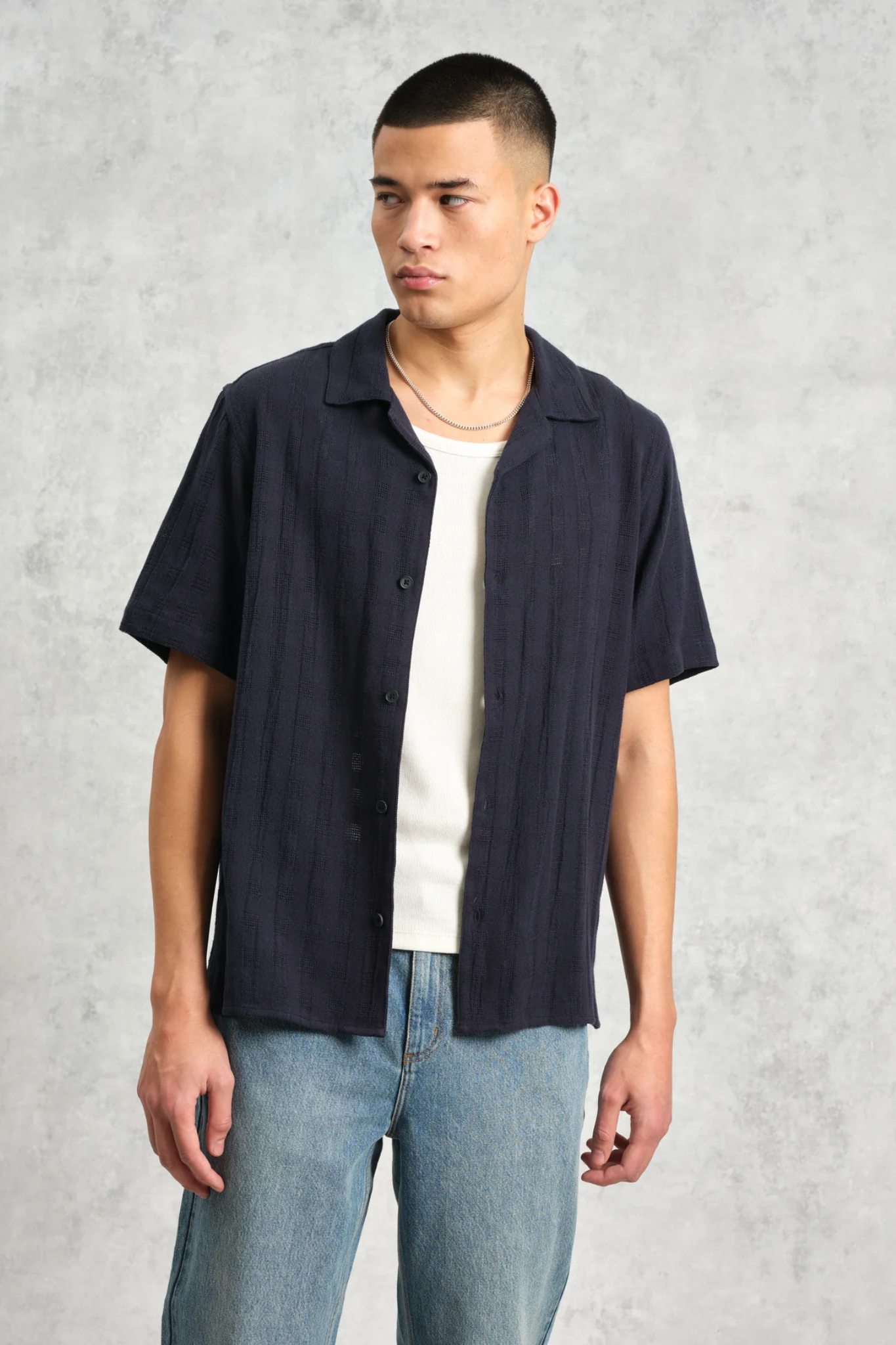 Model wearing the Wax London didcot box open weave grid shirt in navy. Front view