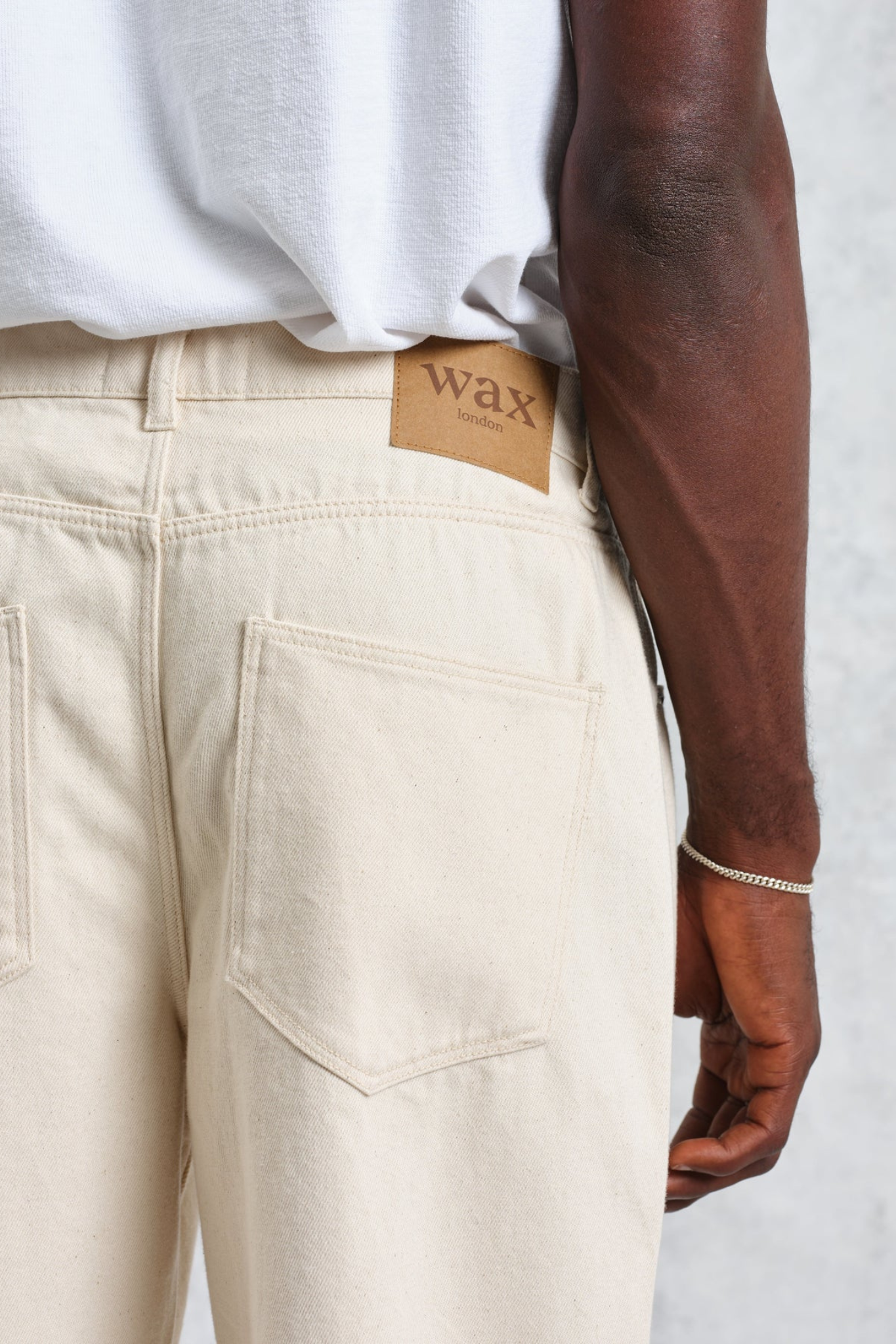 Model wearing the Wax London felix loose fit denim jeans in ecru. Close back view