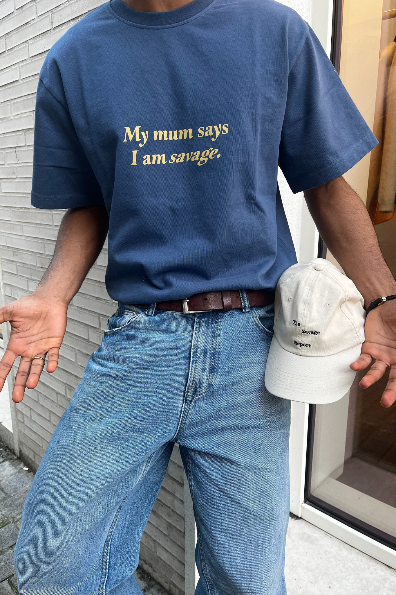 Model wearing The Savage Report my mom t-shirt in blue. Front view