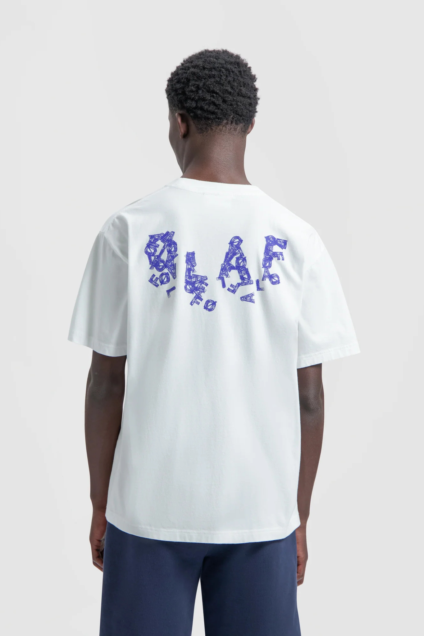 Model wearing the Olaf ink logo t-shirt in white and logo in blue. Back view