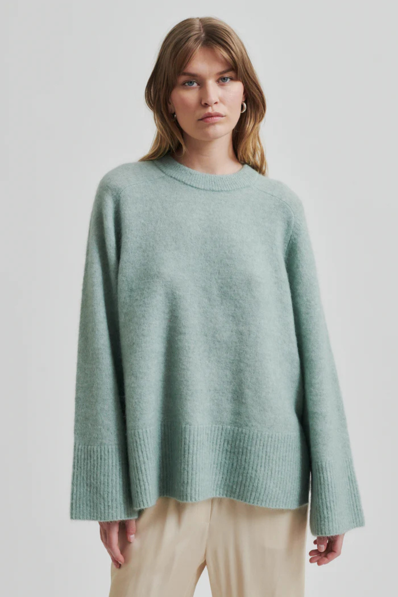 Model wearing the Second Female brookline raglan o-neck knit in green. Front view