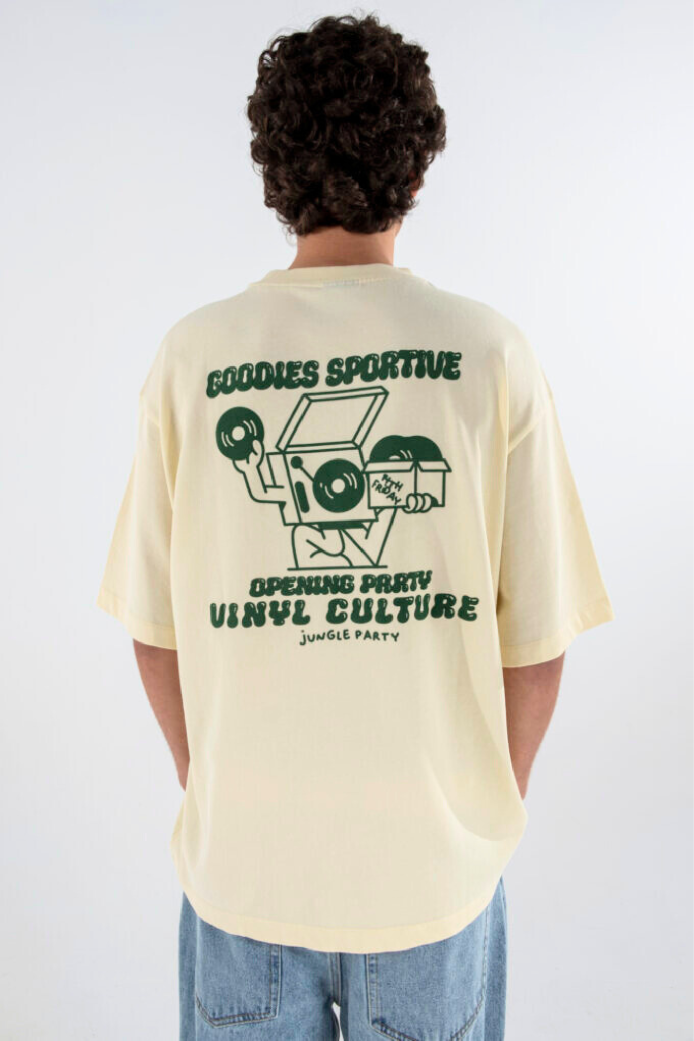 Model wearing the Goodies Sportive vinyl culture t-shirt in butter and graphic in green. Back view