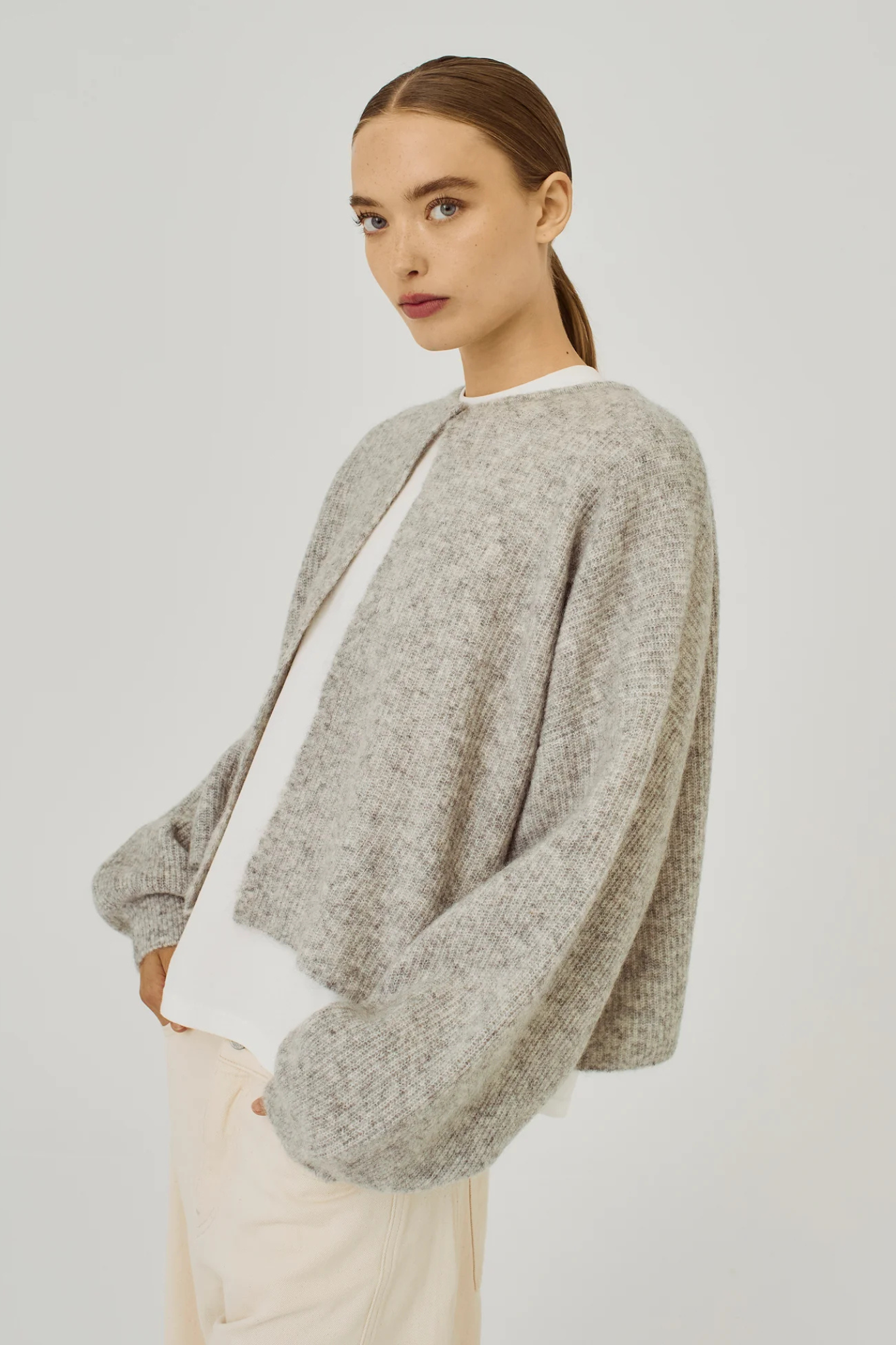 Model wearing the Norr hazina knit cardigan in light grey melange. Front view