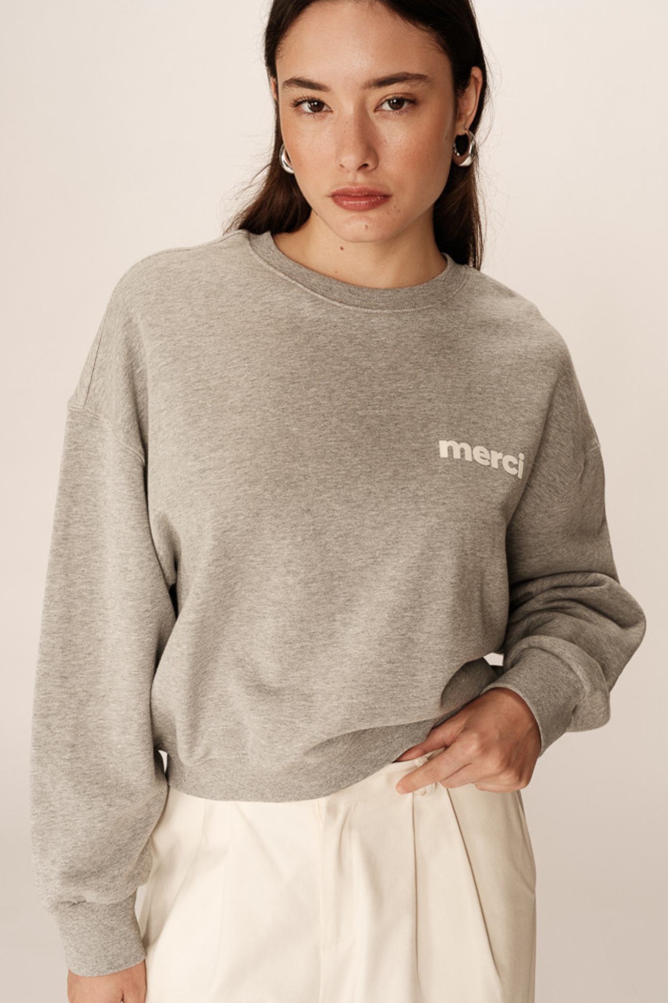 Model wearing the Grace & Mila positive merci sweater in grey. Front view