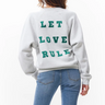 Model wearing the Catwalk Junkie grey graphic sweater with letters in green. Back view