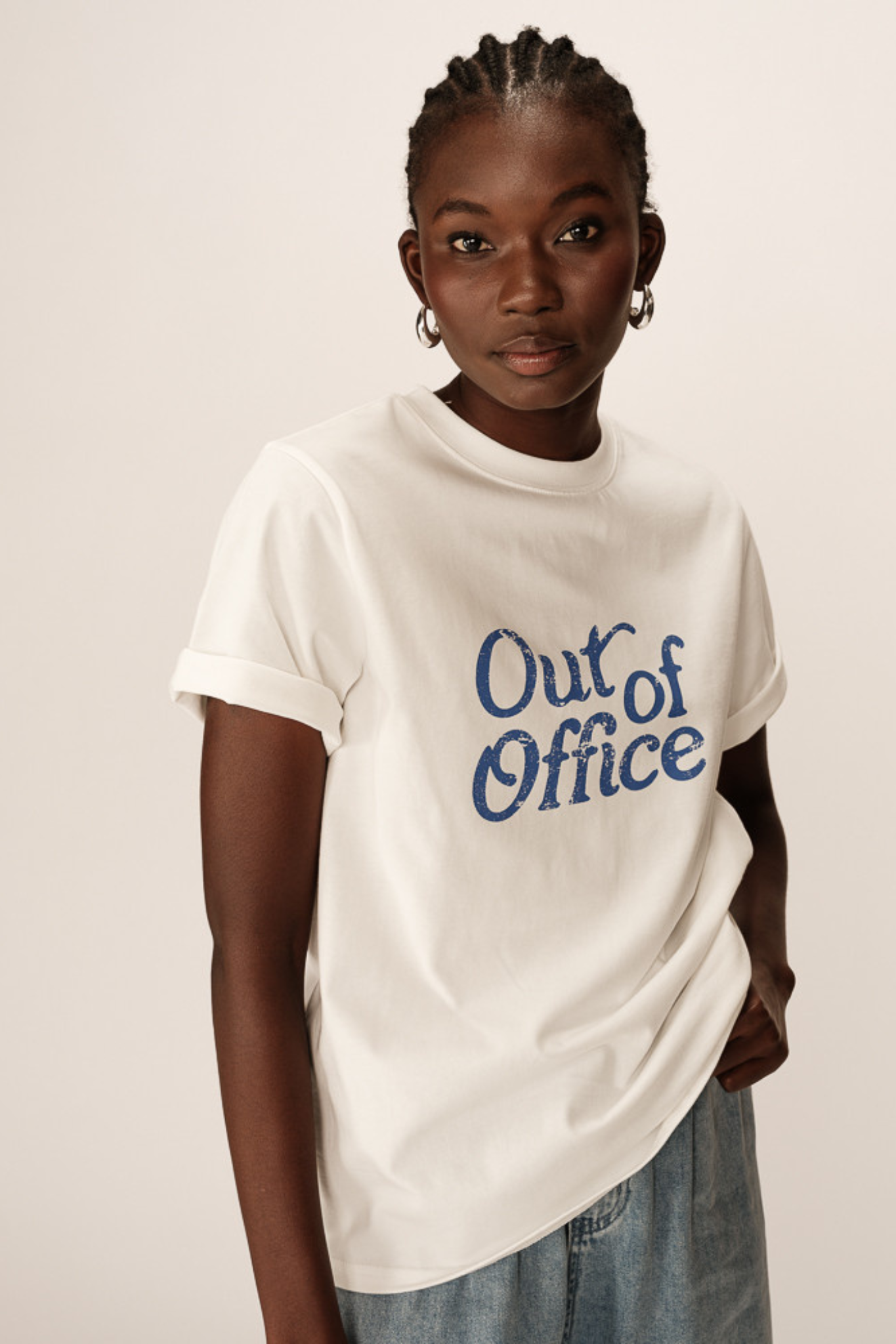 Model wearing the Grace & Mila white prelude out of office t-shirt with text in blue. Front view