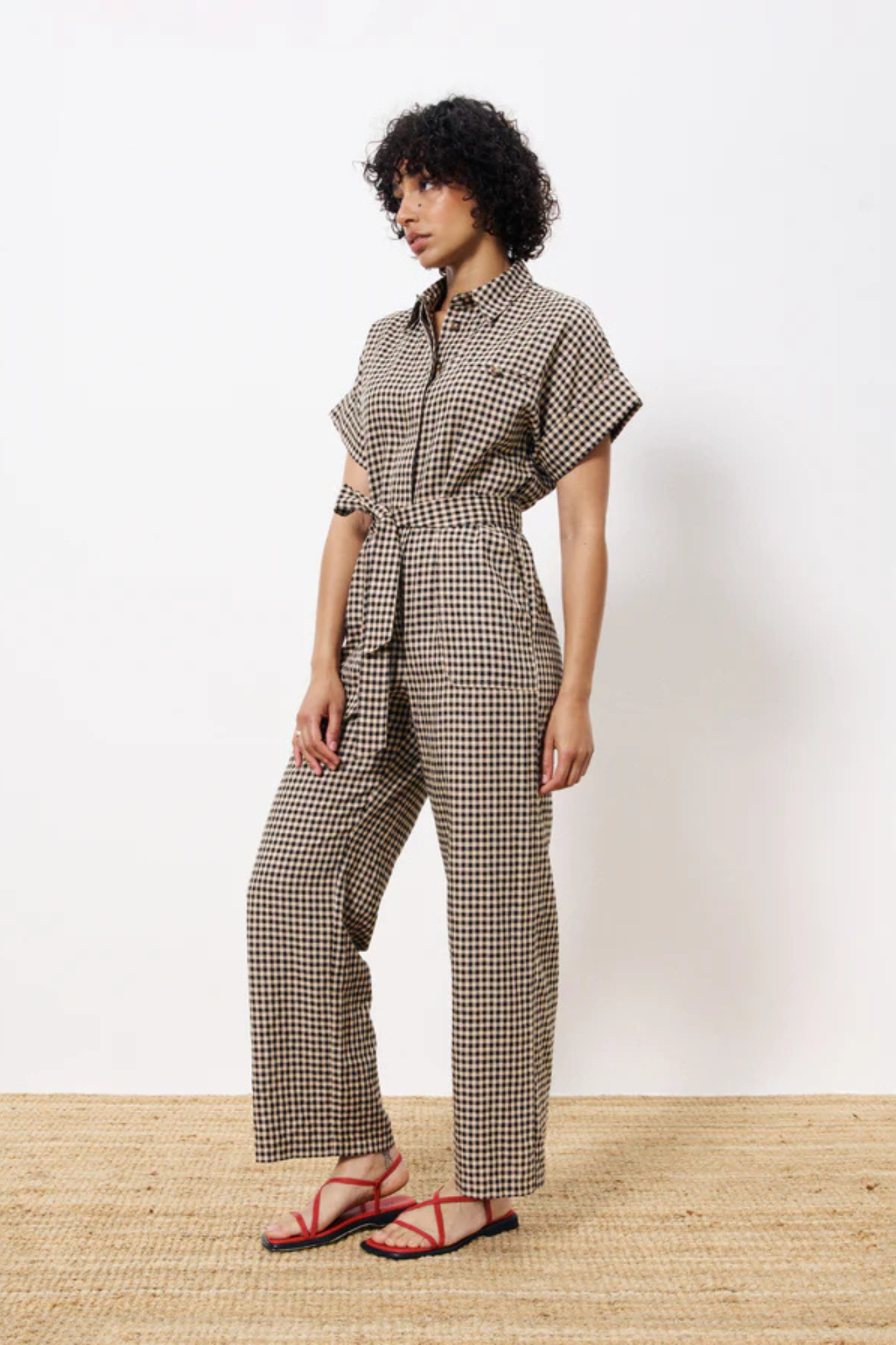 Model wearing the FRNCH elfie jumpsuit in black and beige checked. Front view