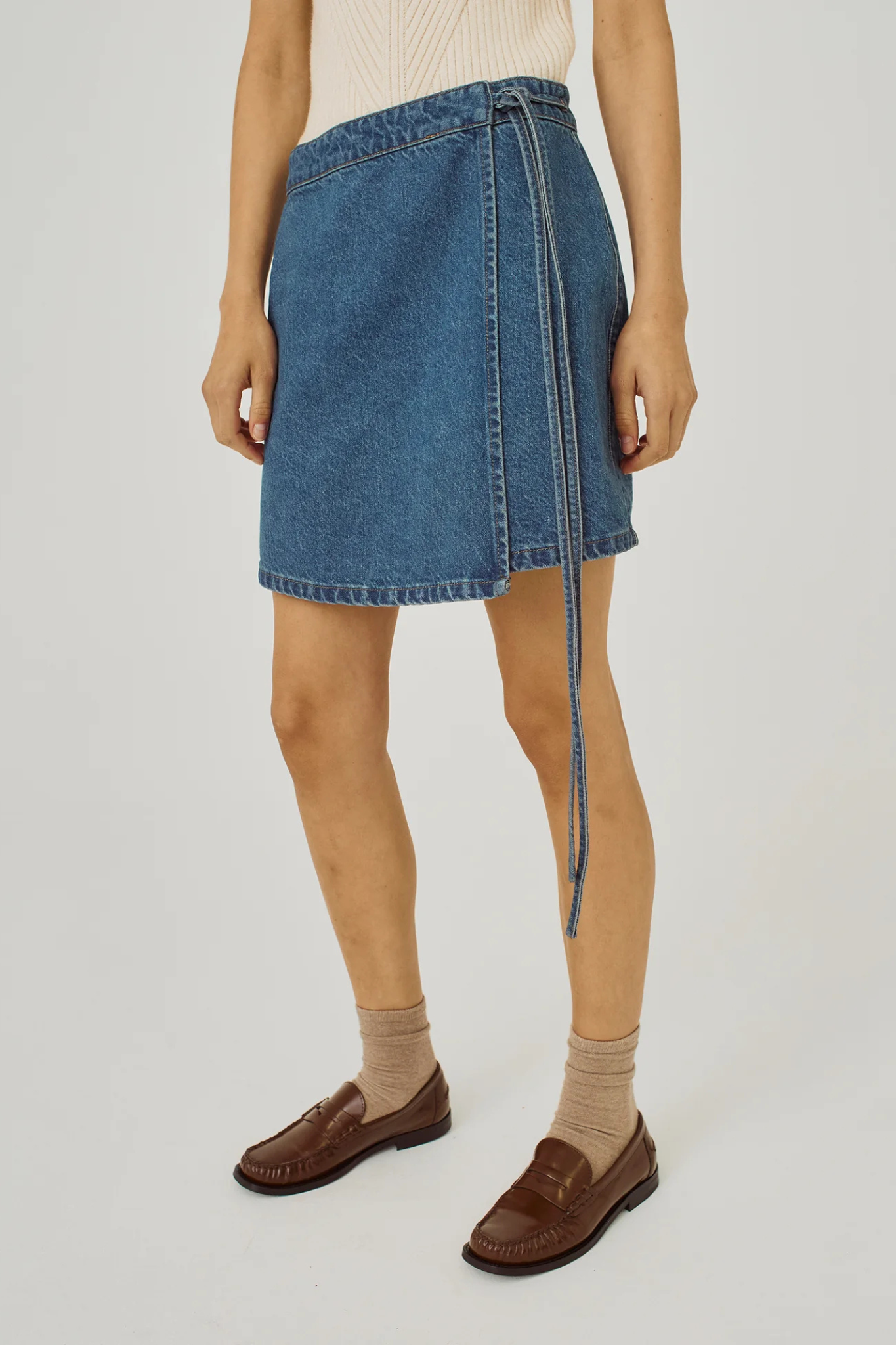 Model wearing the Norr ninni tie denim skirt in blue. Front view