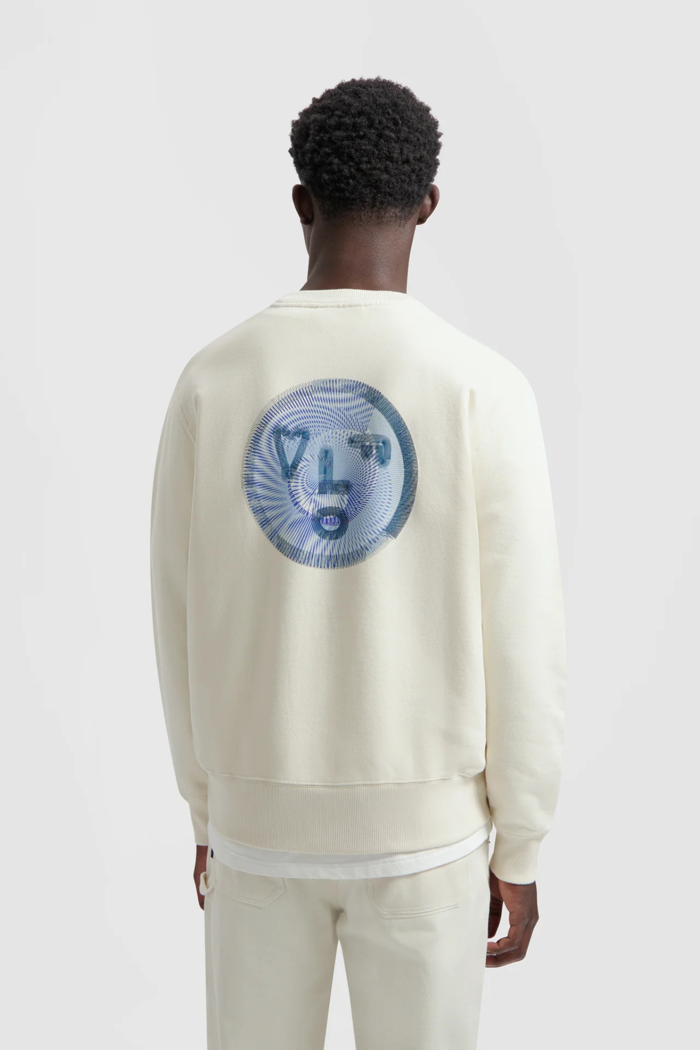 Model wearing the Olaf spiral face crewneck sweater in white and face in blue. Back view