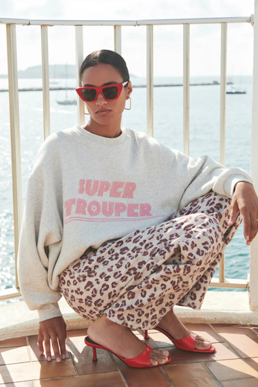 Model wearing the By-Bar grey bibi trouper sweater with letters in pink. Front view