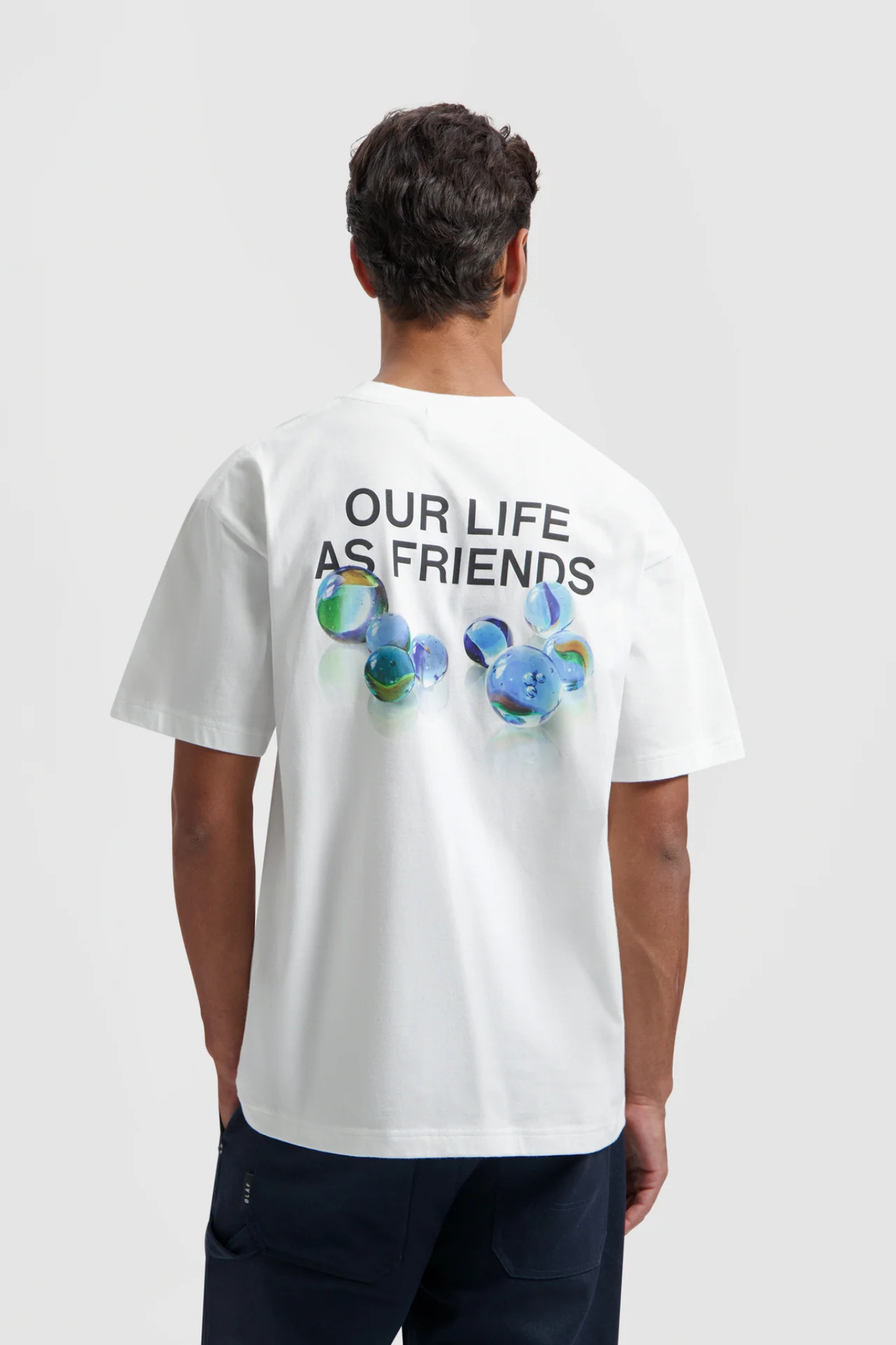 Model wearing the Olaf marbles t-shirt in white and graphic in blue. Back view