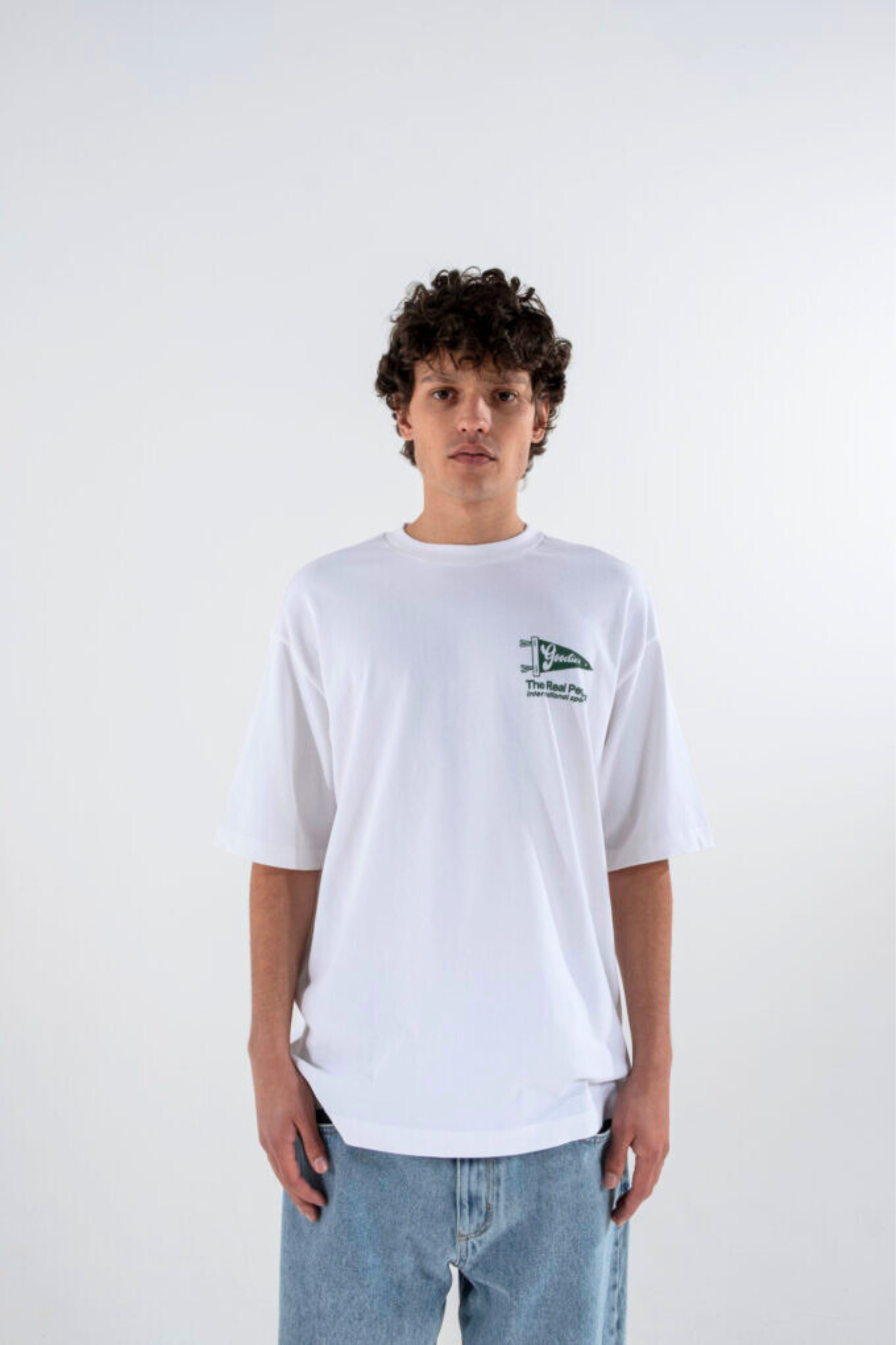 Model wearing the Goodies Sportive flag t-shirt in white and graphic in green. Front view