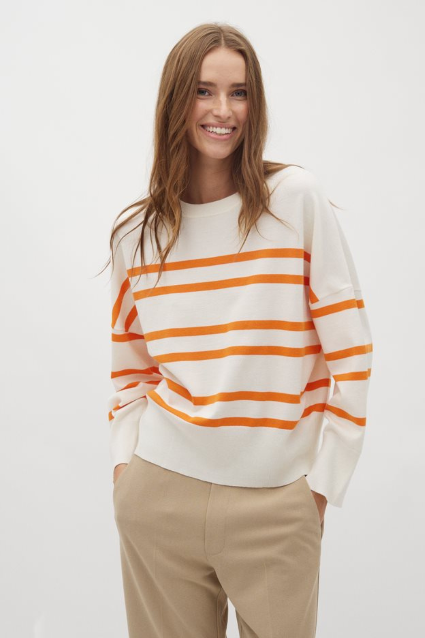 Model wearing the Mbym gillian bravana knit in white and orange. Front view