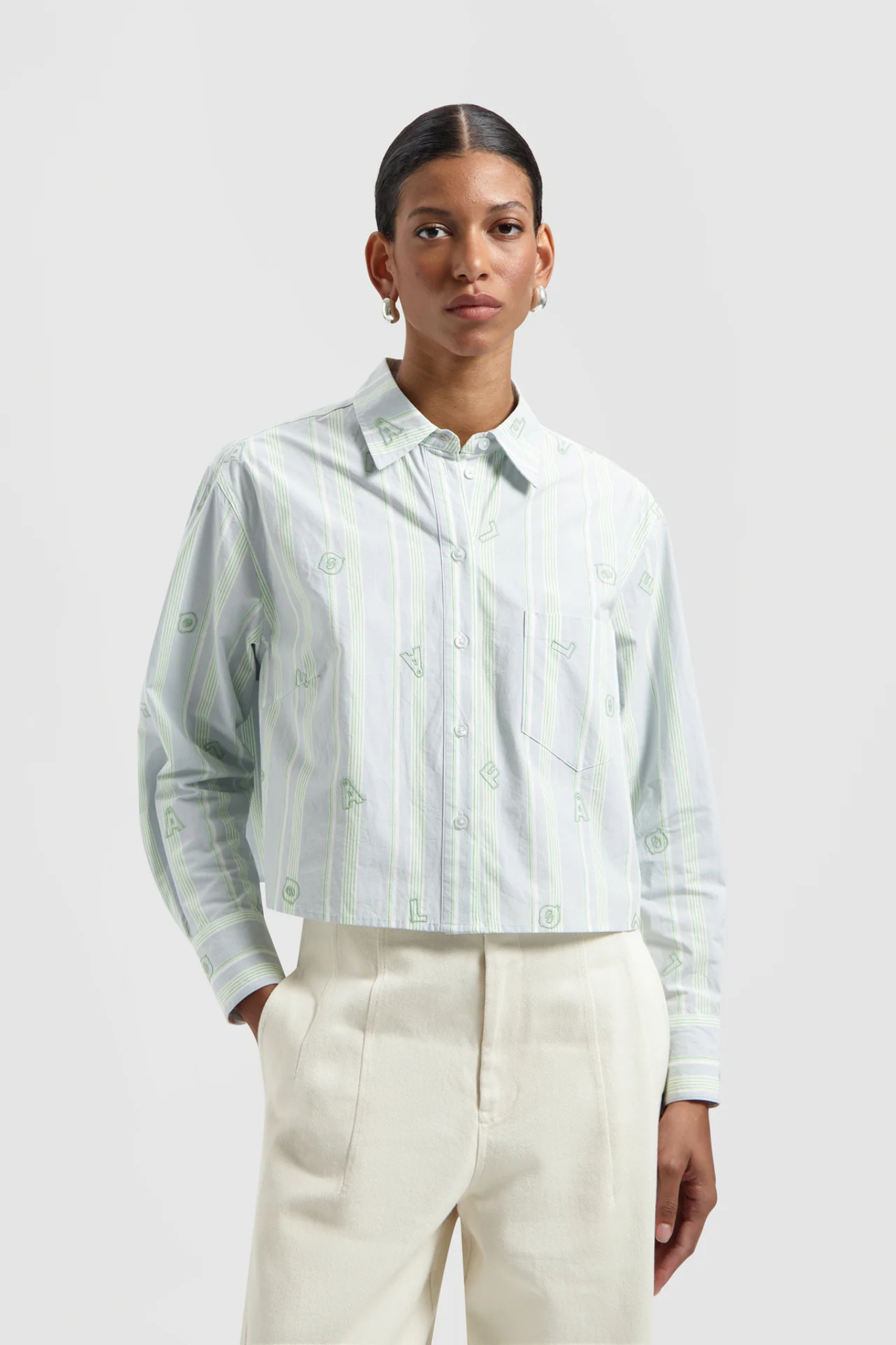 Model wearing the Olaf embro logo stripe cropped shirt in green and blue. Front view