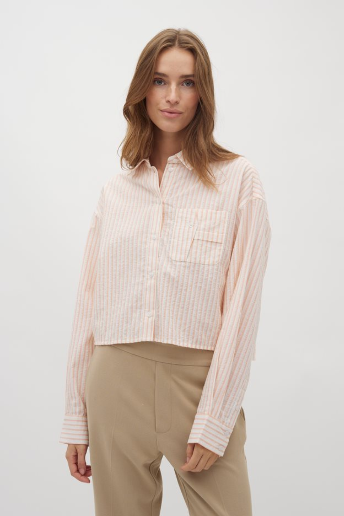 Model wearing the Mbym emmelia deserae shirt in white with orange stripes. Front view