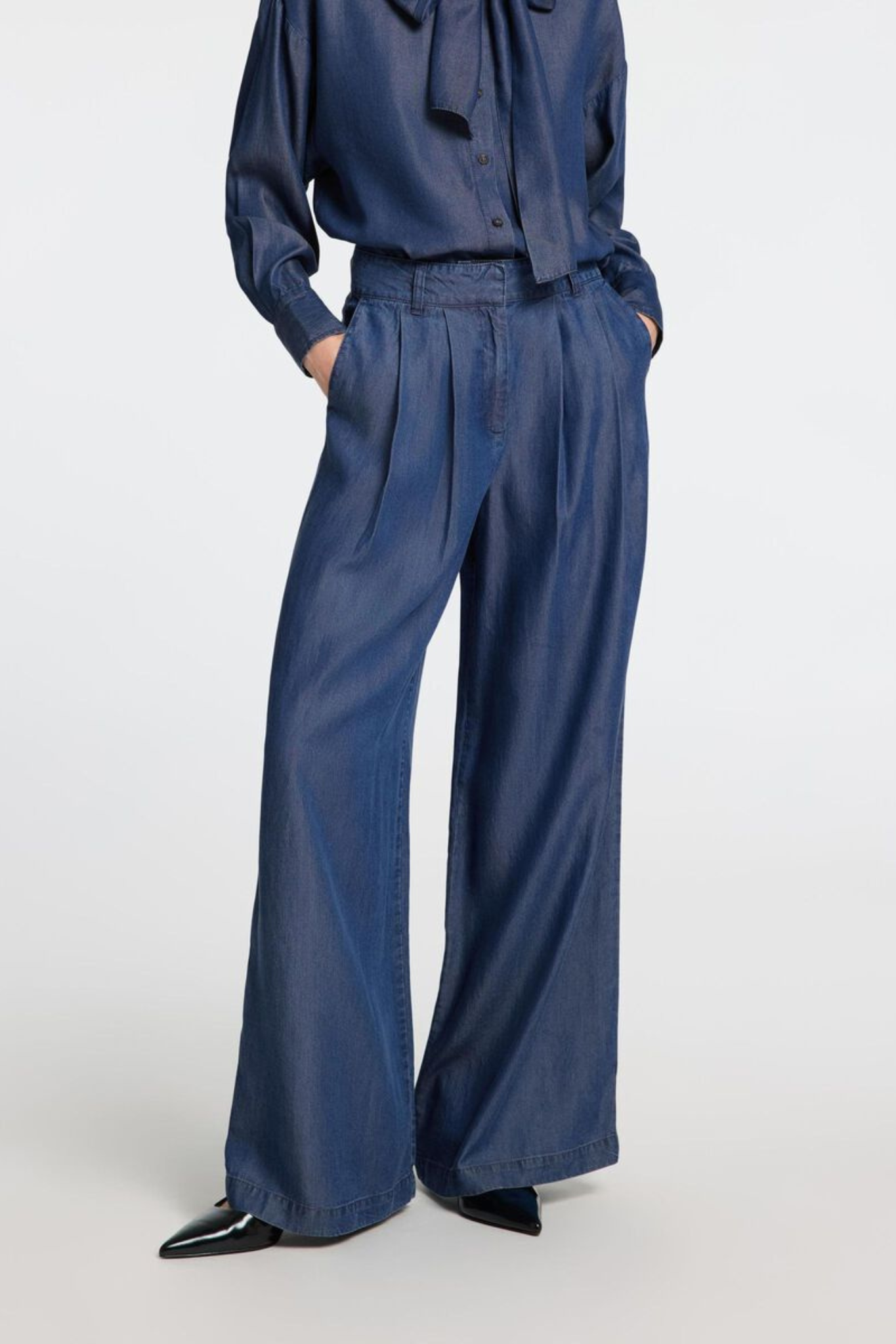 Model wearing the Selected Femme janna pleated chambray pants in dark blue. Front view