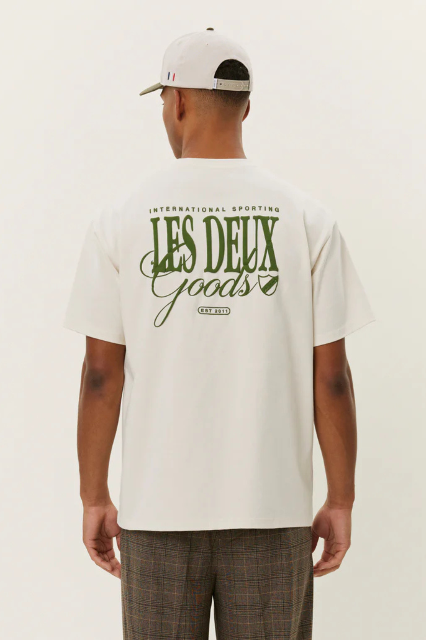 Model wearing the Les Deux goods t-shirt in ivory and green. Back view