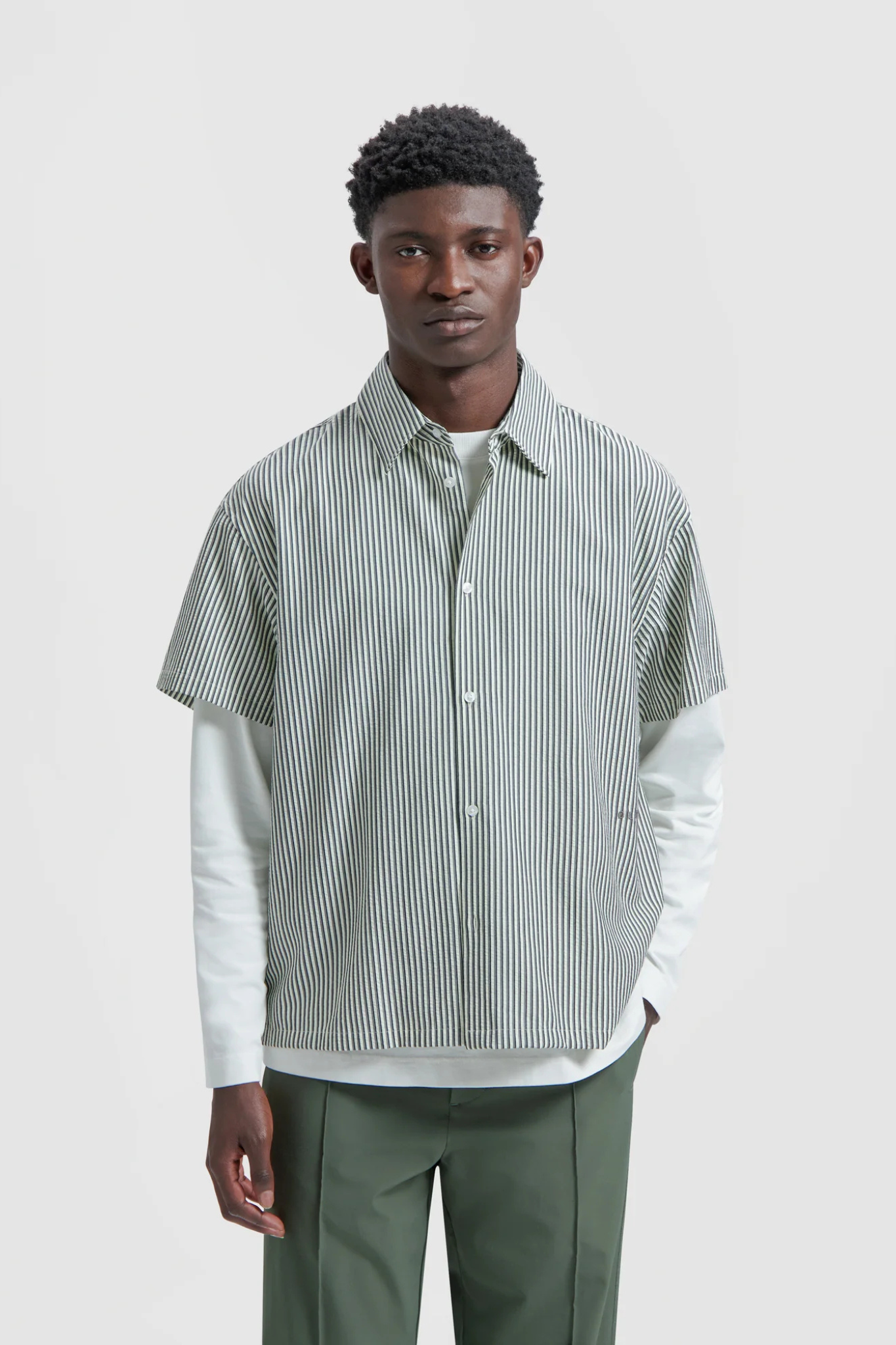 Model wearing the Olaf boxy seersucker stripe shirt in white and green. Front view