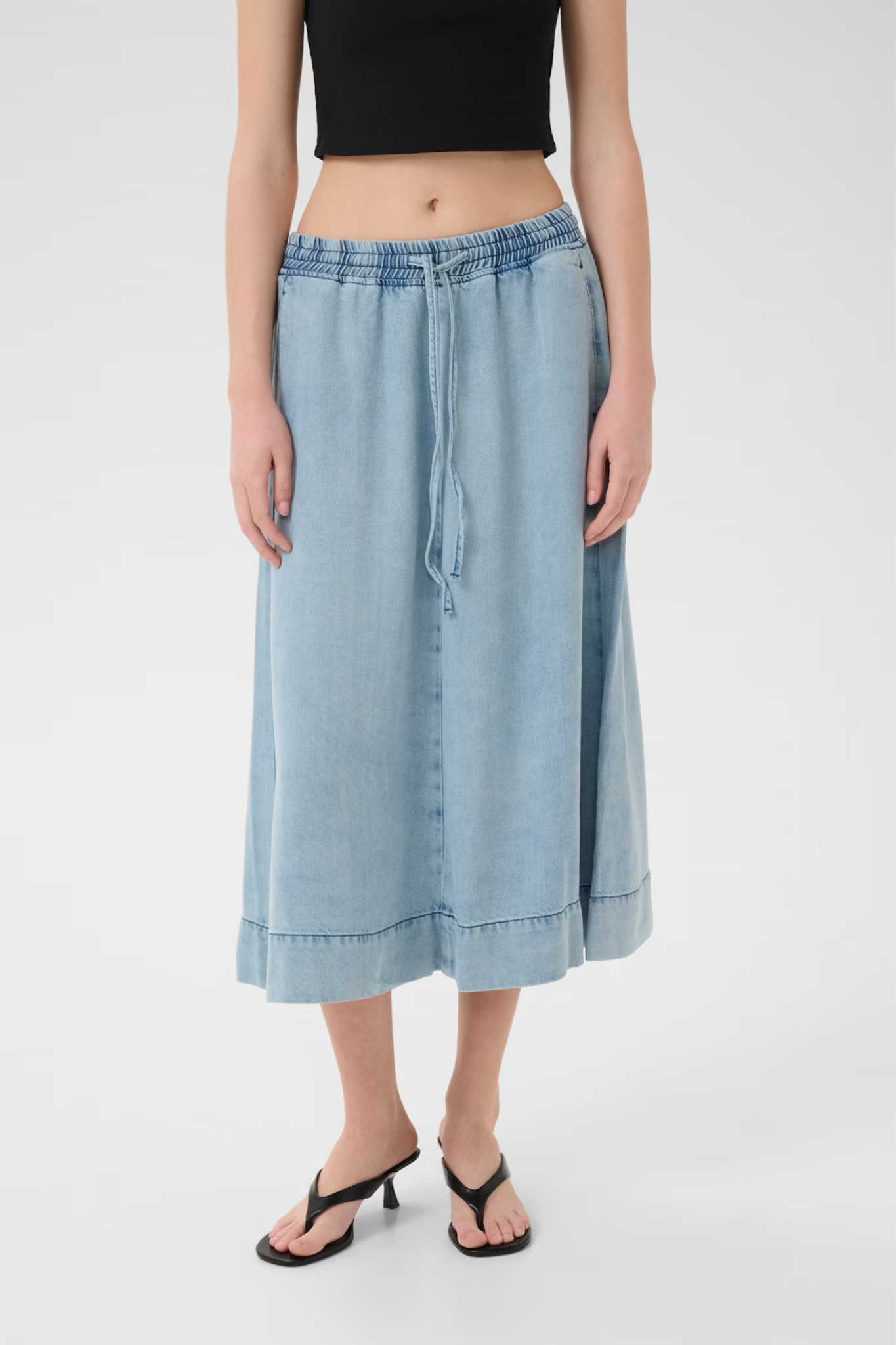 Model wearing the Gestuz felina long skirt in light blue washed. Front view