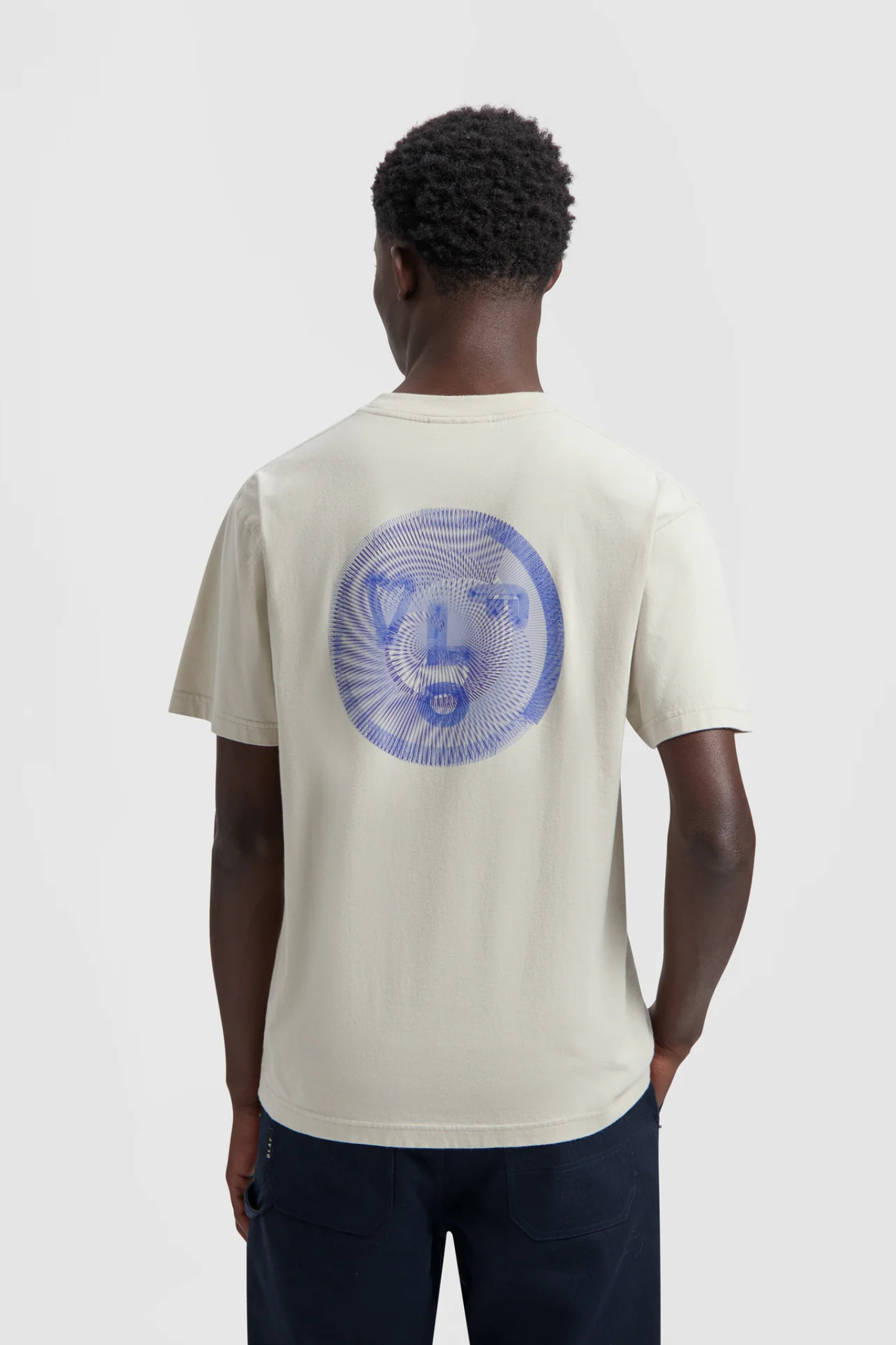 Model wearing the Olaf spiral face t-shirt in beige and face in blue. Back view