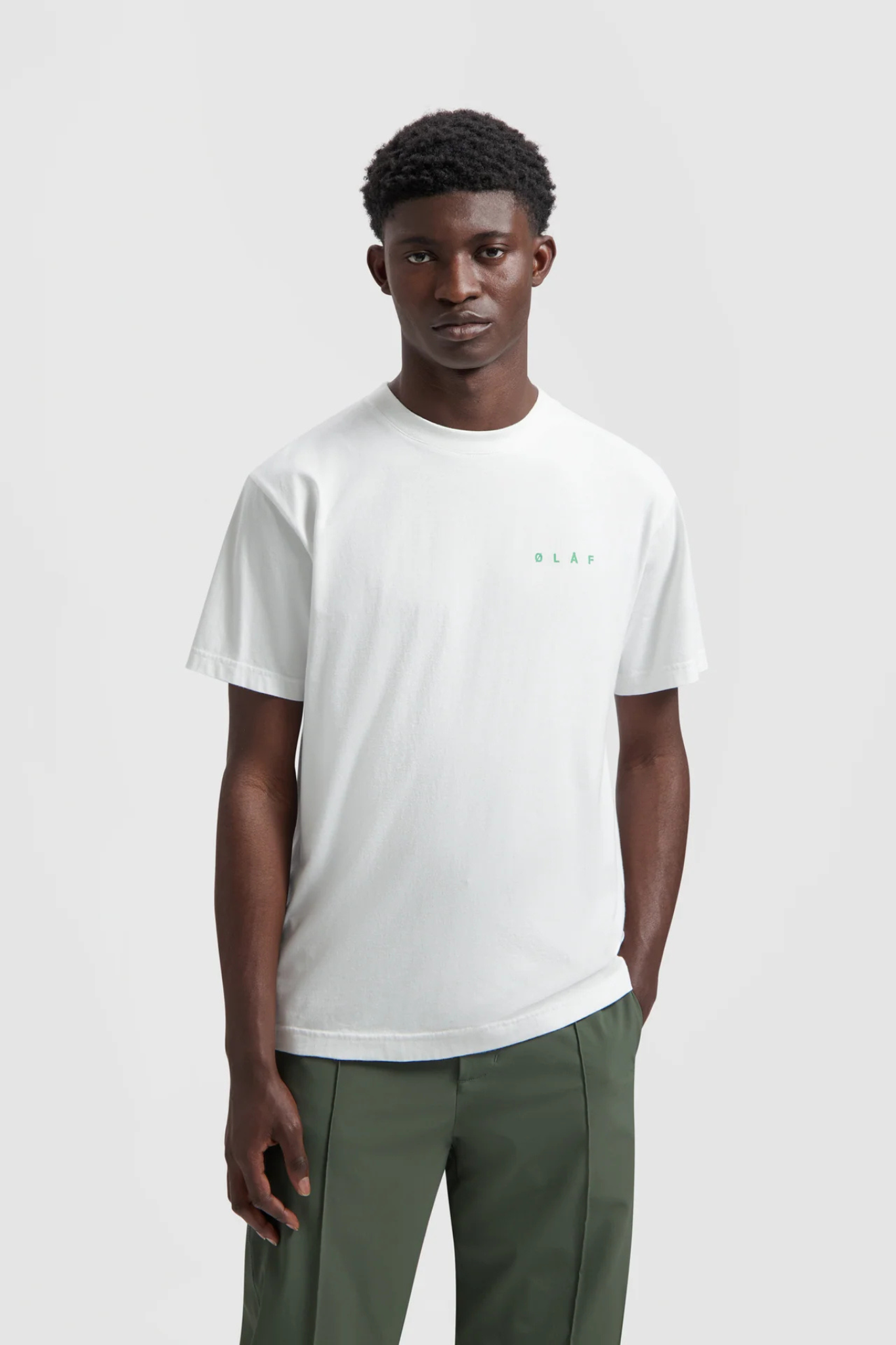 Model wearing the Olaf spiral face t-shirt in white and face in green. Front view